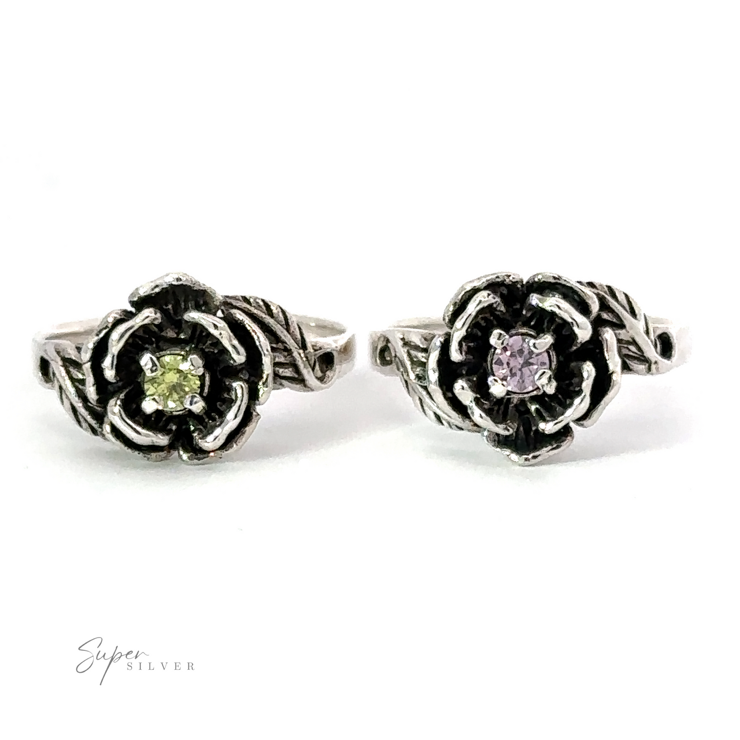 Two floral-shaped sterling silver Rose Rings With Cubic Zirconia Stone feature a central green gemstone on the left ring and a central purple gemstone on the right ring, both with intricate band designs. The small stones are crafted to sparkle like Cubic Zirconia. Logo text reads "Super Silver.