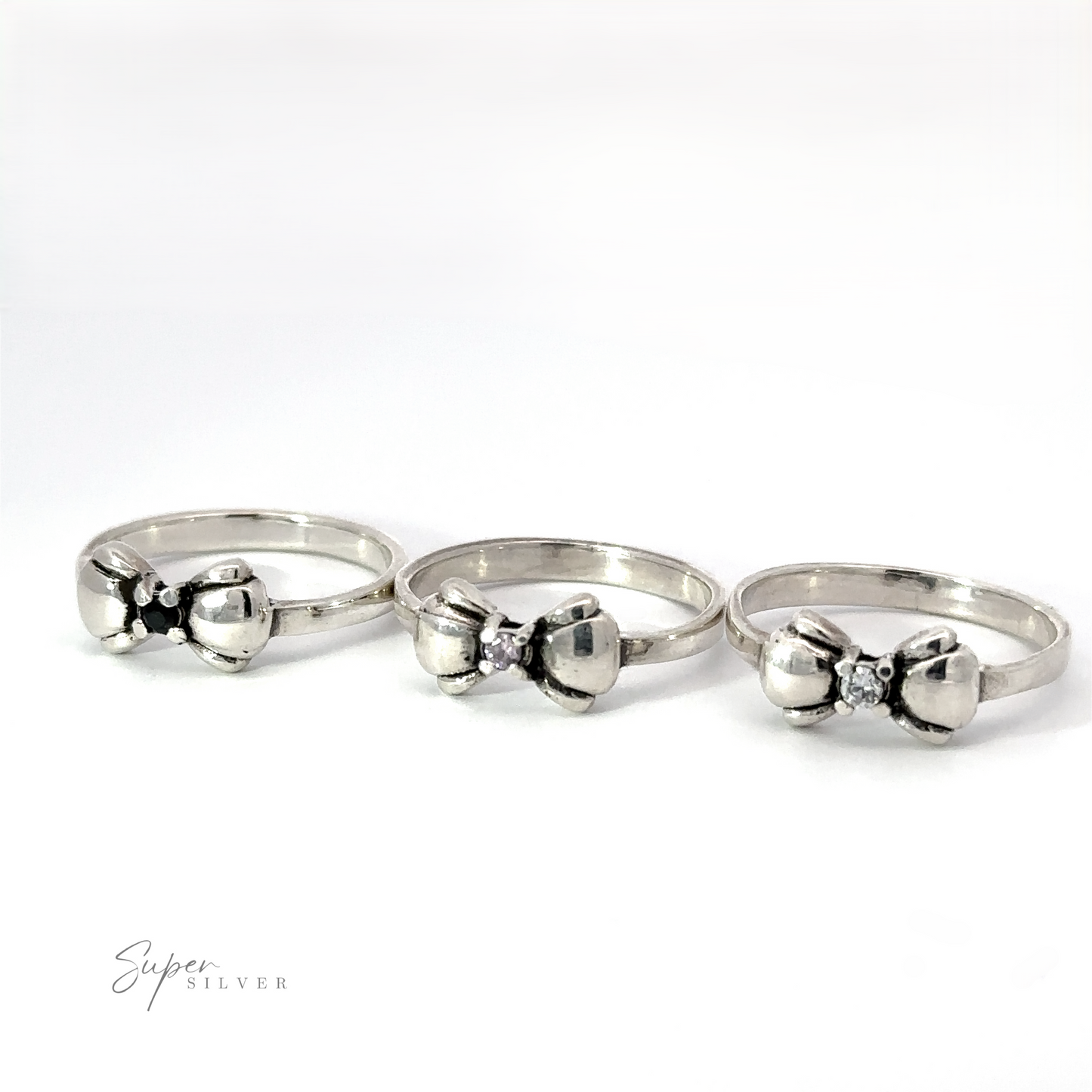 
                  
                    Three Adorable Cubic Zirconia Bow Rings with elegant designs are displayed in a row on a plain background. The middle bow ring appears slightly larger. The text "Super Silver" is in the lower left corner.
                  
                