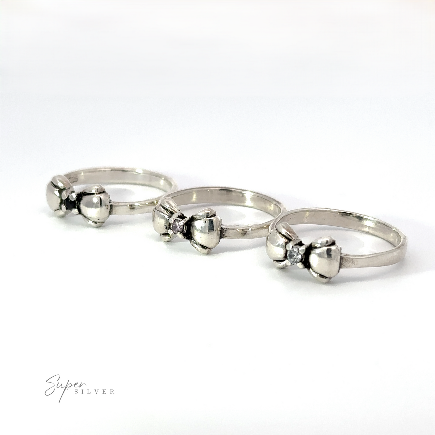 Three Adorable Cubic Zirconia Bow Rings, each adorned with a small bow, are lined up side by side on a white surface. The text "Super Silver" is in the bottom left corner.