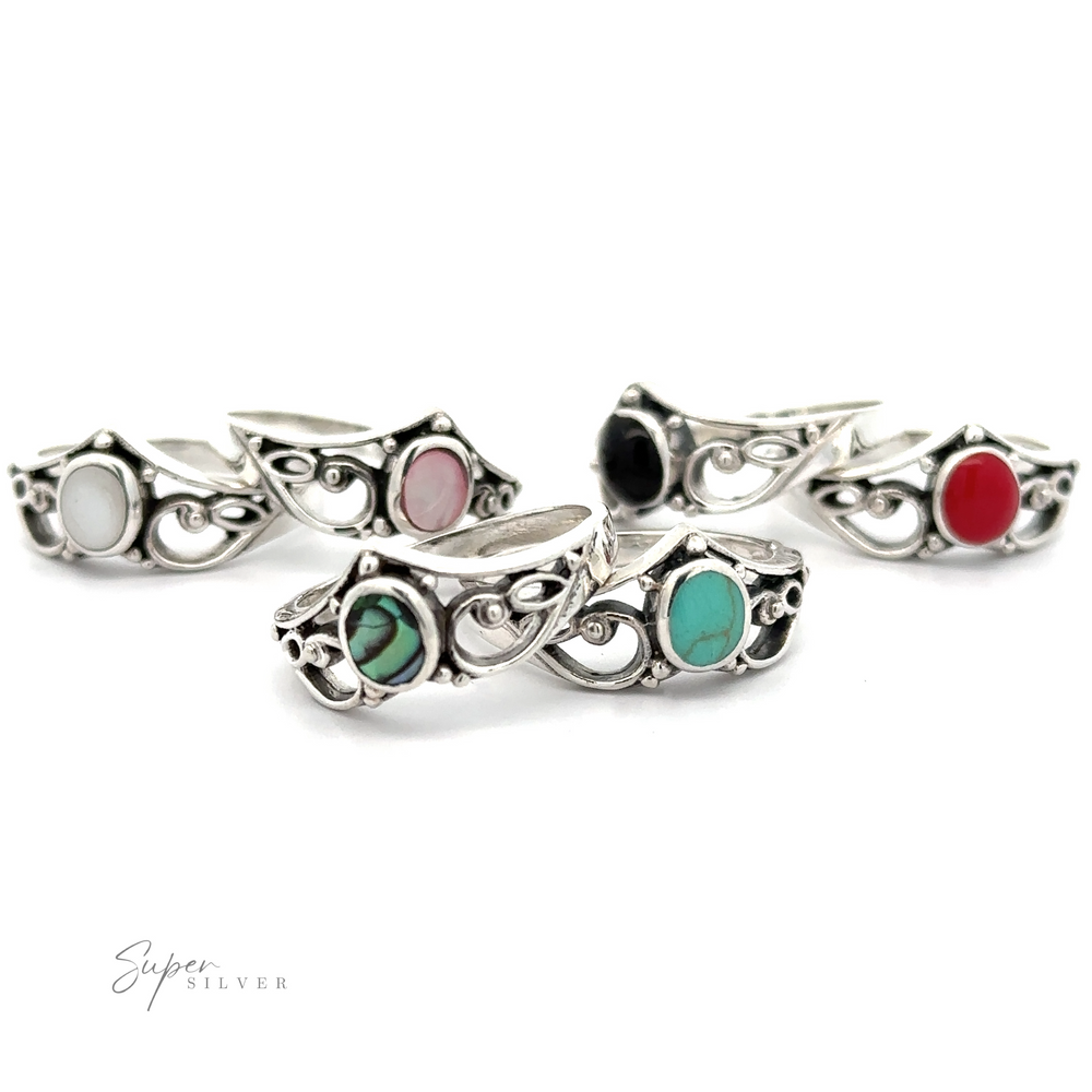 A group of silver rings with Filigree Crown Ring with Inlaid Oval Stone and different colored stones, exuding a vintage vibe.