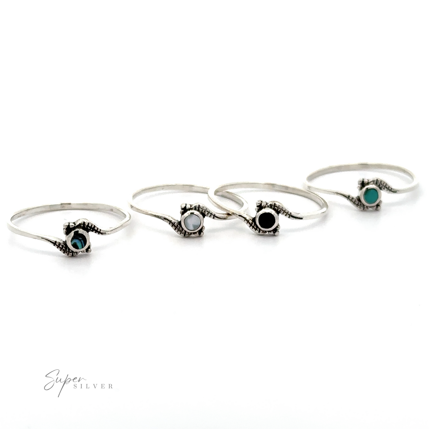 Four Tiny Freeform Rings with Round Inlaid Stones, including turquoise and mother of pearl, displayed in a row against a white background.