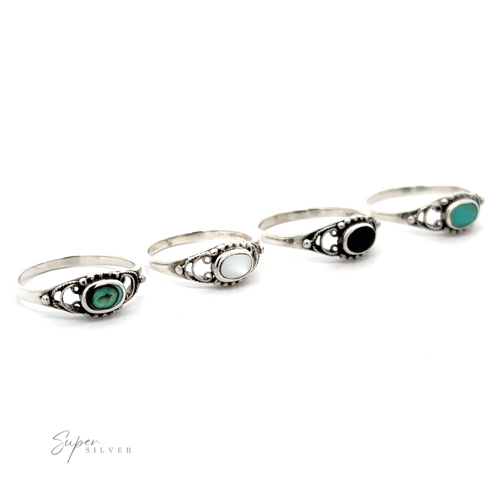 
                  
                    Four sterling silver rings with green and black stones, including an oval stone ring with a delicate border.
                  
                