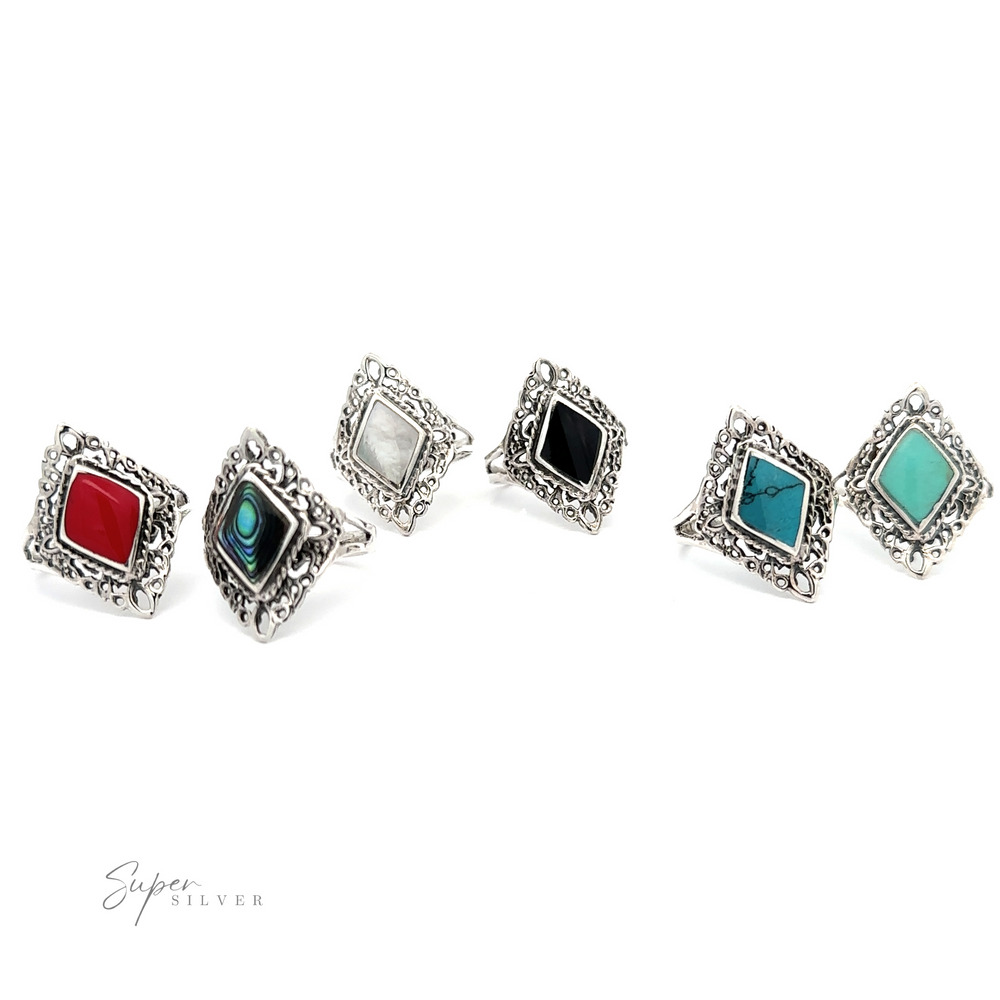 A group of diamond shaped filigree rings with inlaid stones in different colors of gemstones.