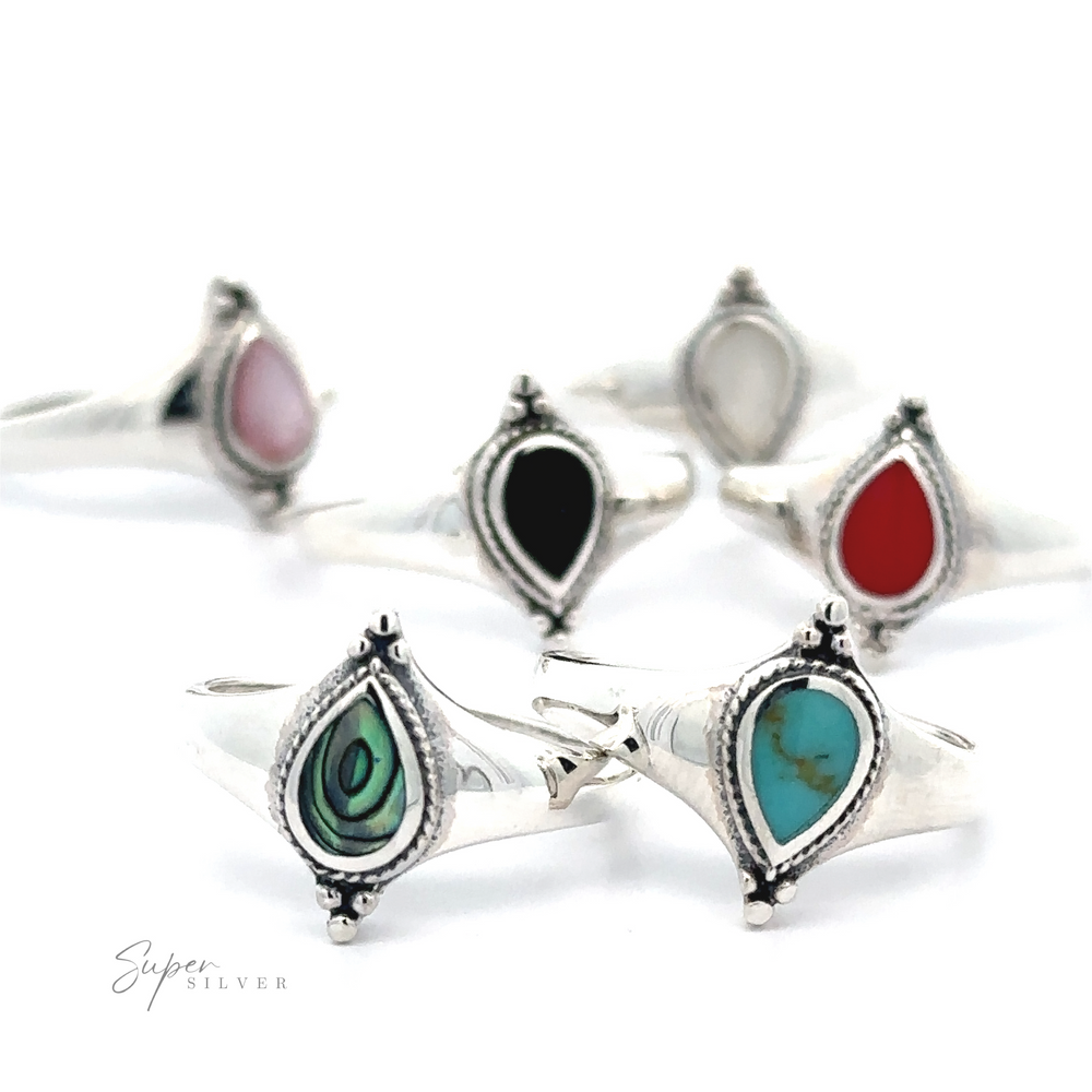 A collection of Teardrop Inlay Shield Rings with various colored stones displayed against a white background.