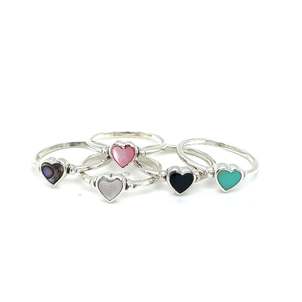 A set of four Dainty Inlaid Heart Rings adorned with stones on a white background.