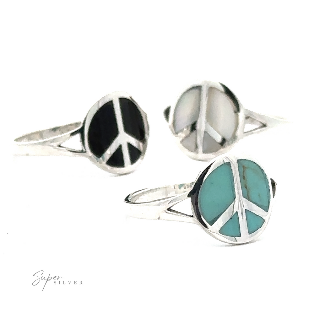 Three Stone Inlay Peace Sign Rings, each featuring a symbol in black onyx, white, and turquoise. The rings are displayed with the brand name "Super Silver" visible in the corner.
