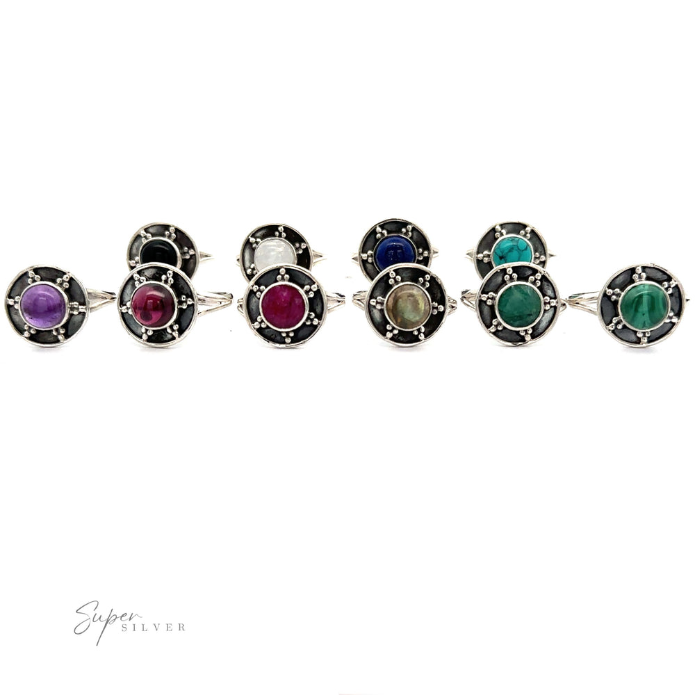 
                  
                    A row of ten Gemstone Rings With Unique Oxidized Design with various colored stones, including purple, red, blue, green, and white, set in decorative sterling silver bands. The background is white. The logo "Super Silver" is visible.
                  
                