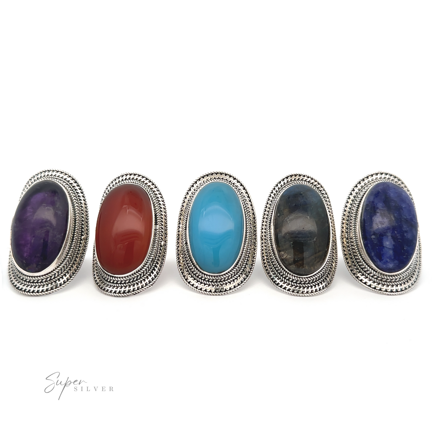 Five Large Oval Shield Gemstone Rings with different colored oval gemstones—purple, red, turquoise, black, and blue—arranged in a row on a white background. Each ring exudes a bohemian flair. "Super Silver" text is visible in the lower-left corner.
