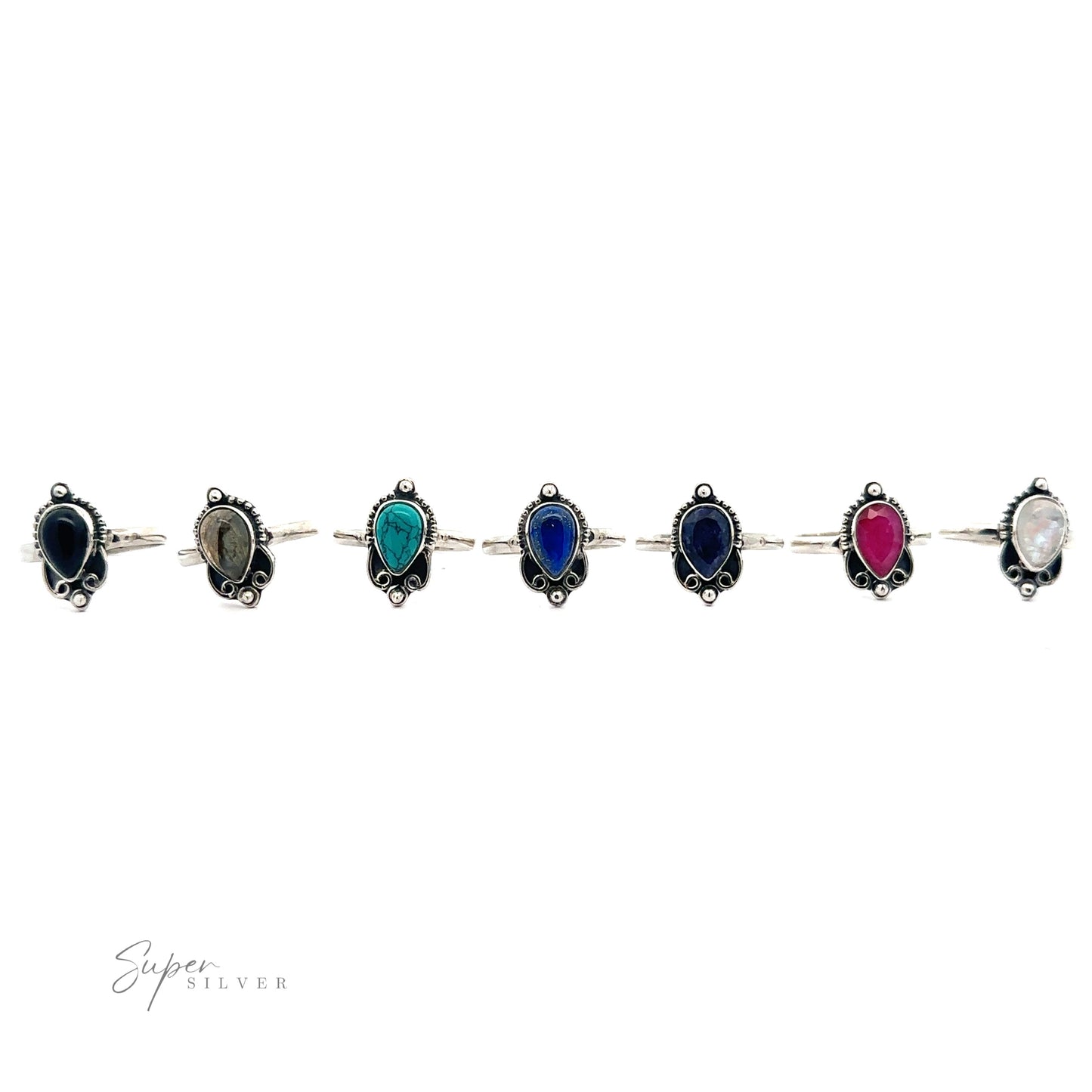 
                  
                    A Vintage Inspired Teardrop Gemstone Ring with alternating oval gemstones in black, green, blue, red, and white, set against a white background.
                  
                