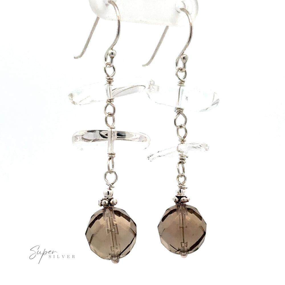 
                  
                    Pair of "Earrings with Clear and Faceted Gray Beads" featuring clear crystal-cut geometric crystals and faceted multicolored beads hanging from the end. "Super Silver" logo is visible in the lower left corner.
                  
                