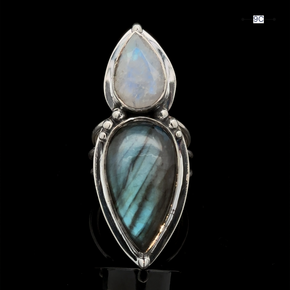 
                  
                    Introducing the Heavy Labradorite And Moonstone Ring, a captivating silver statement piece featuring two teardrop-shaped stones—a mesmerizing moonstone and a radiant labradorite—set against a dark background.
                  
                