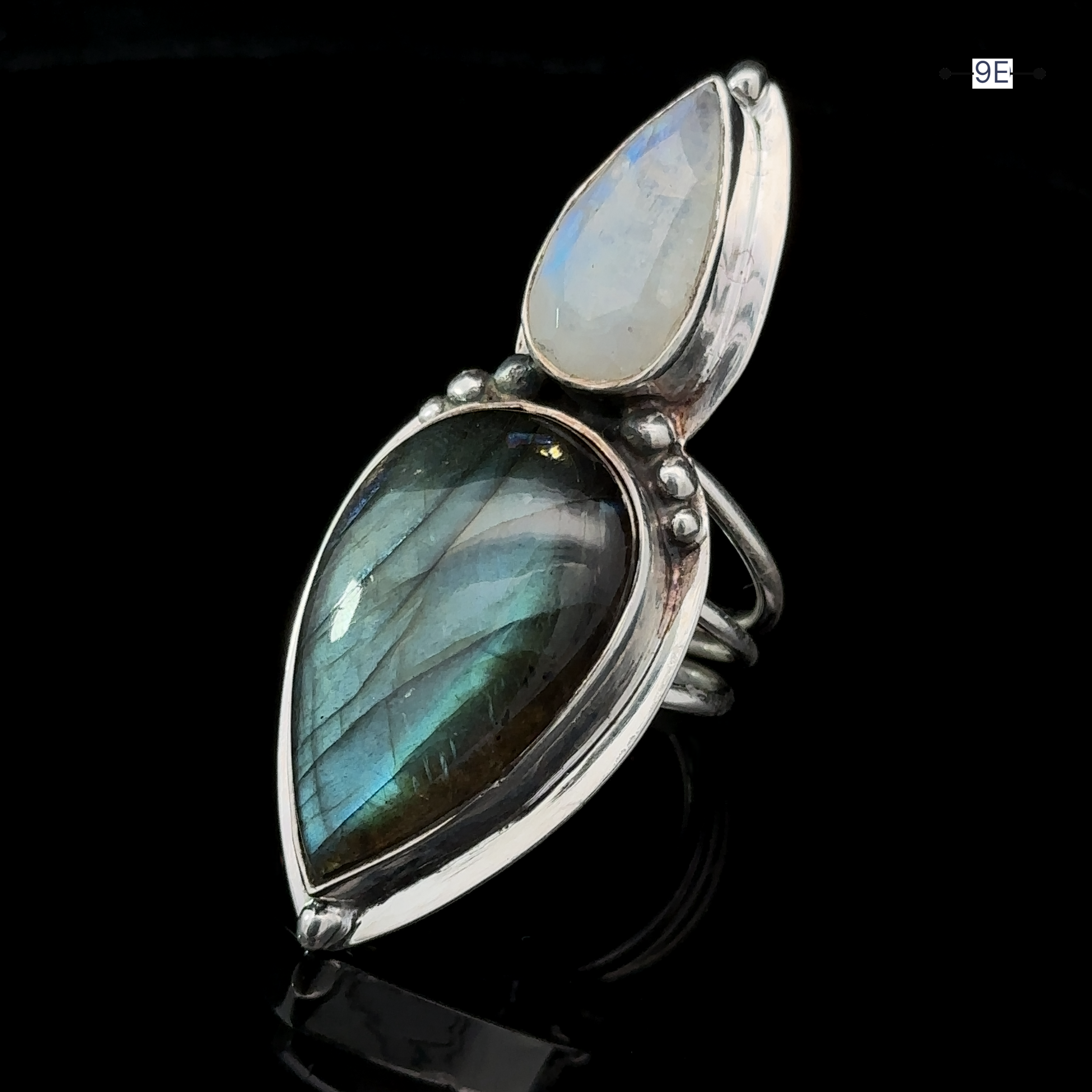 The Heavy Labradorite And Moonstone Ring makes a striking statement with its teardrop-shaped labradorite and smaller oval moonstone, all set against a sleek black background.
