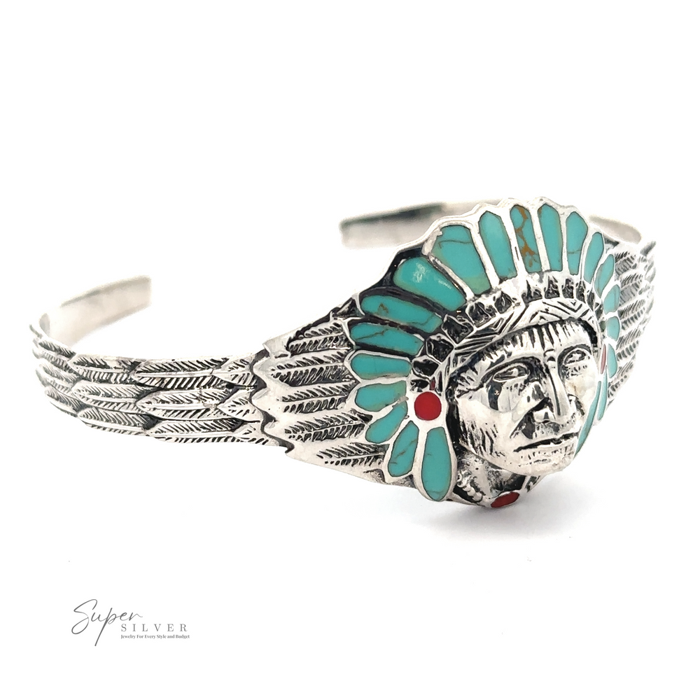 A Chief Head Inlay Stone Cuff featuring an engraved face wearing a detailed headdress adorned with turquoise and red stones. The headdress and band embrace a feather motif, reflecting Native American heritage. The "Super Silver" logo is visible.