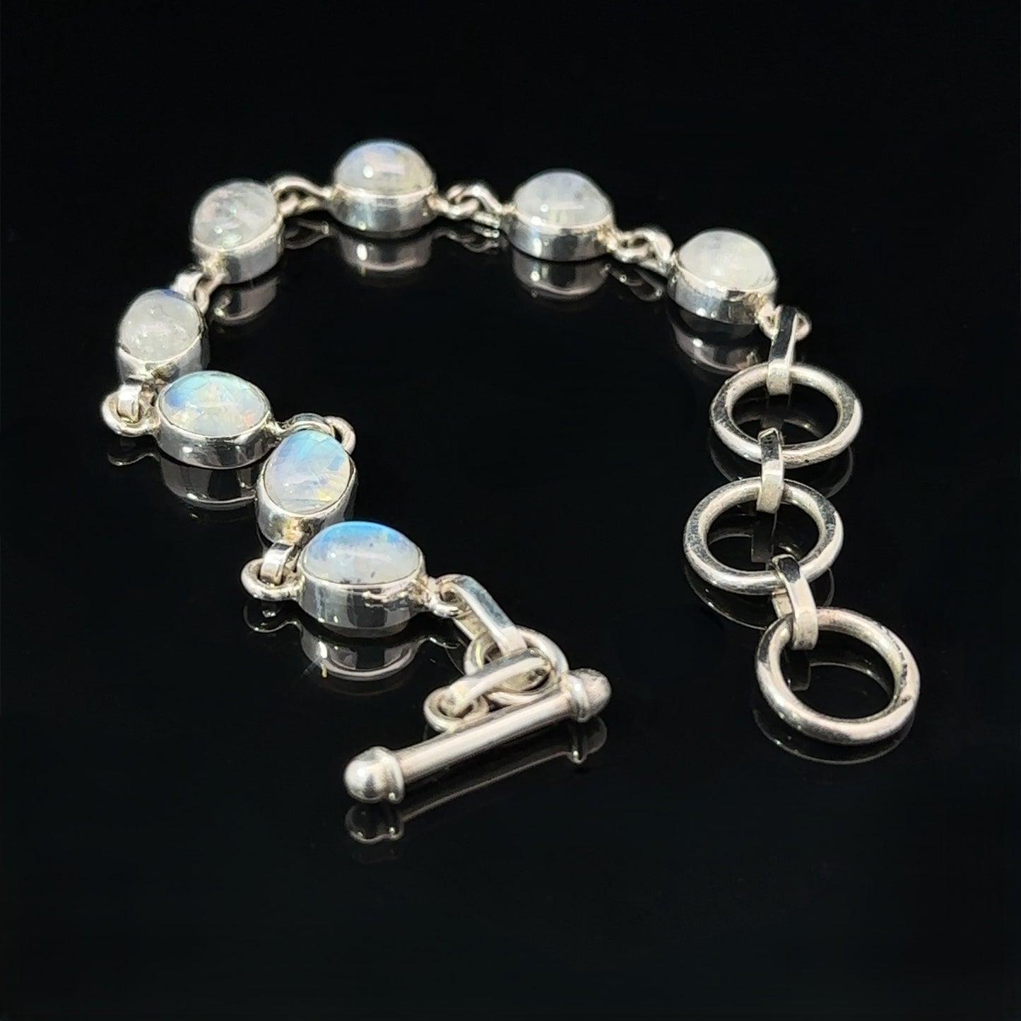 
                  
                    Vibrant Oval Moonstone Bracelet with round moonstone crystal settings and three linked rings for the clasp, displayed on a black background.
                  
                