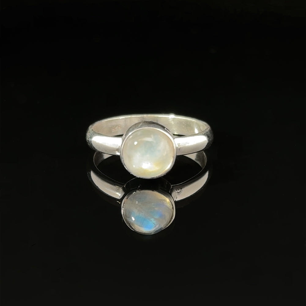 
                  
                    Round Moonstone Ring with a .925 Sterling Silver band reflected on a dark surface.
                  
                
