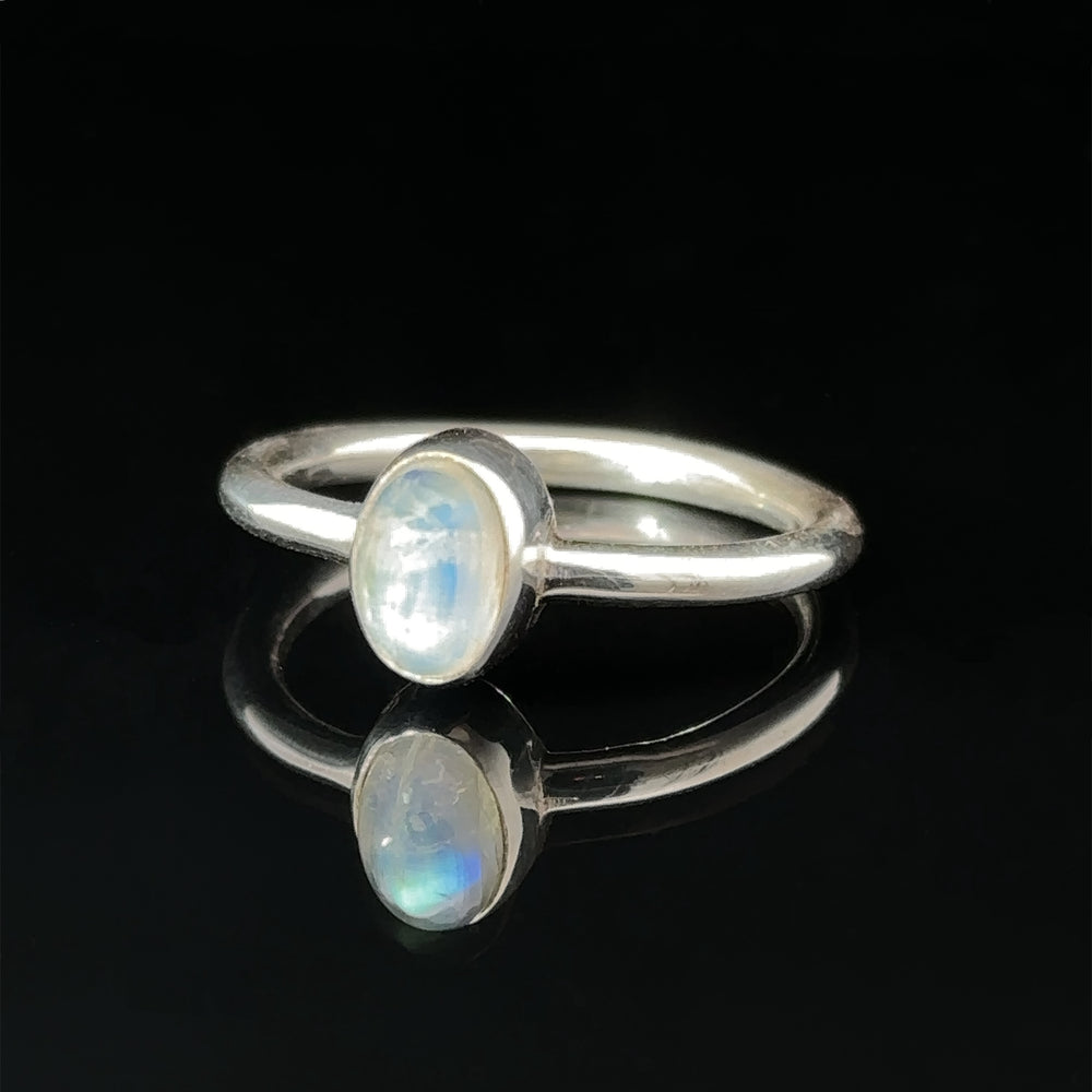 Simple Oval Moonstone Ring with an oval moonstone set on a reflective black surface.