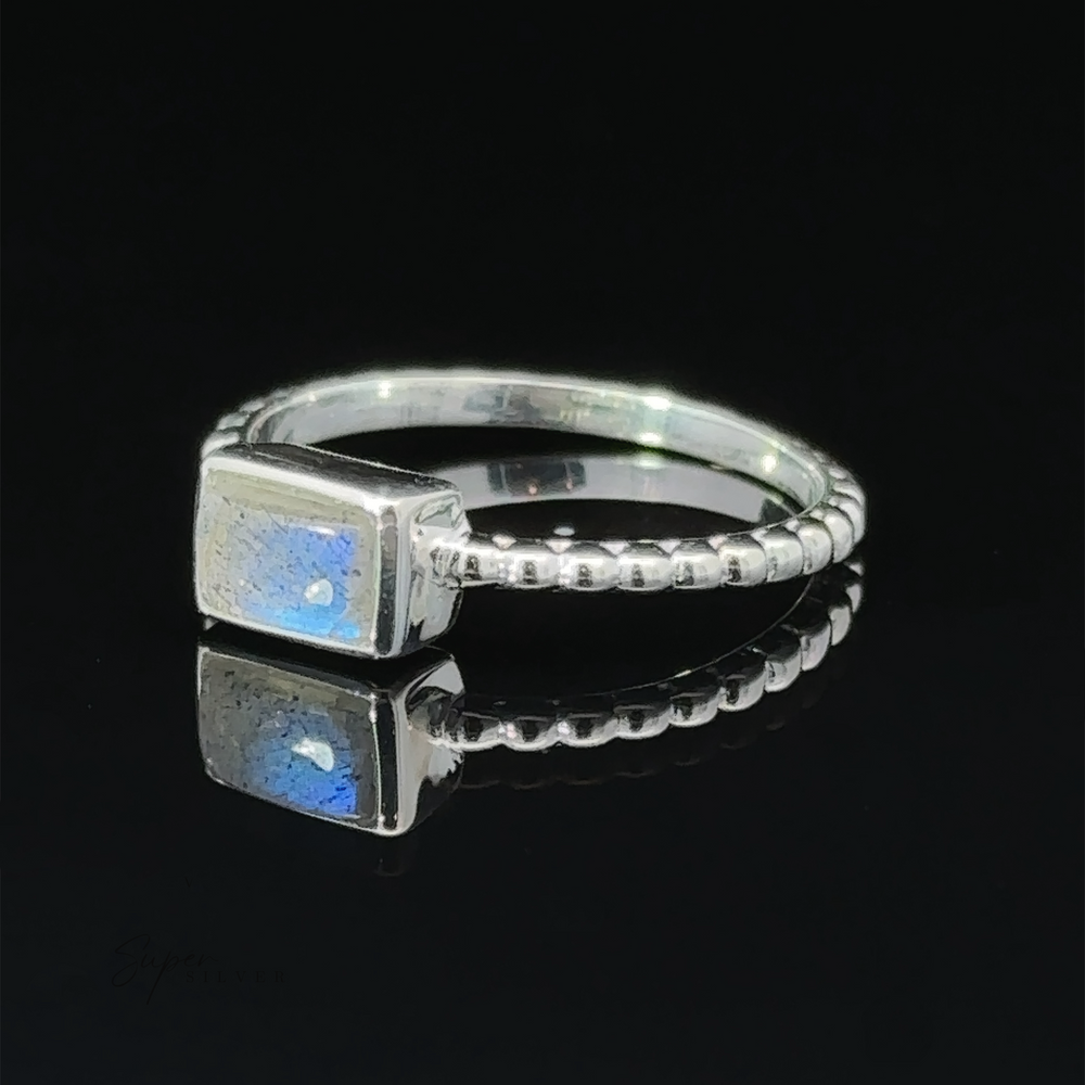 
                  
                    Rectangular Gemstone Ring with Beaded Band displayed on a reflective surface.
                  
                