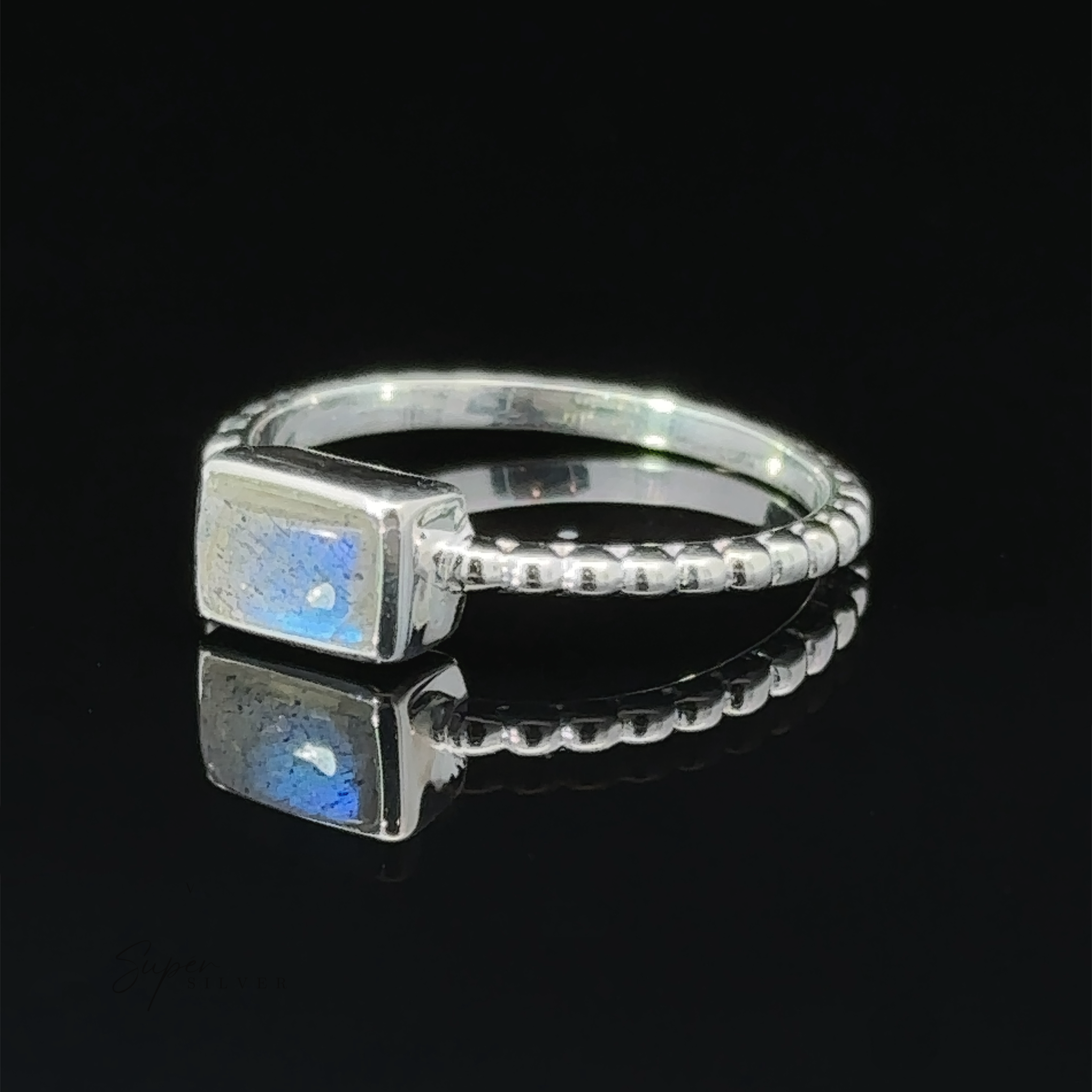 Rectangular Gemstone Ring with Beaded Band displayed on a reflective surface.