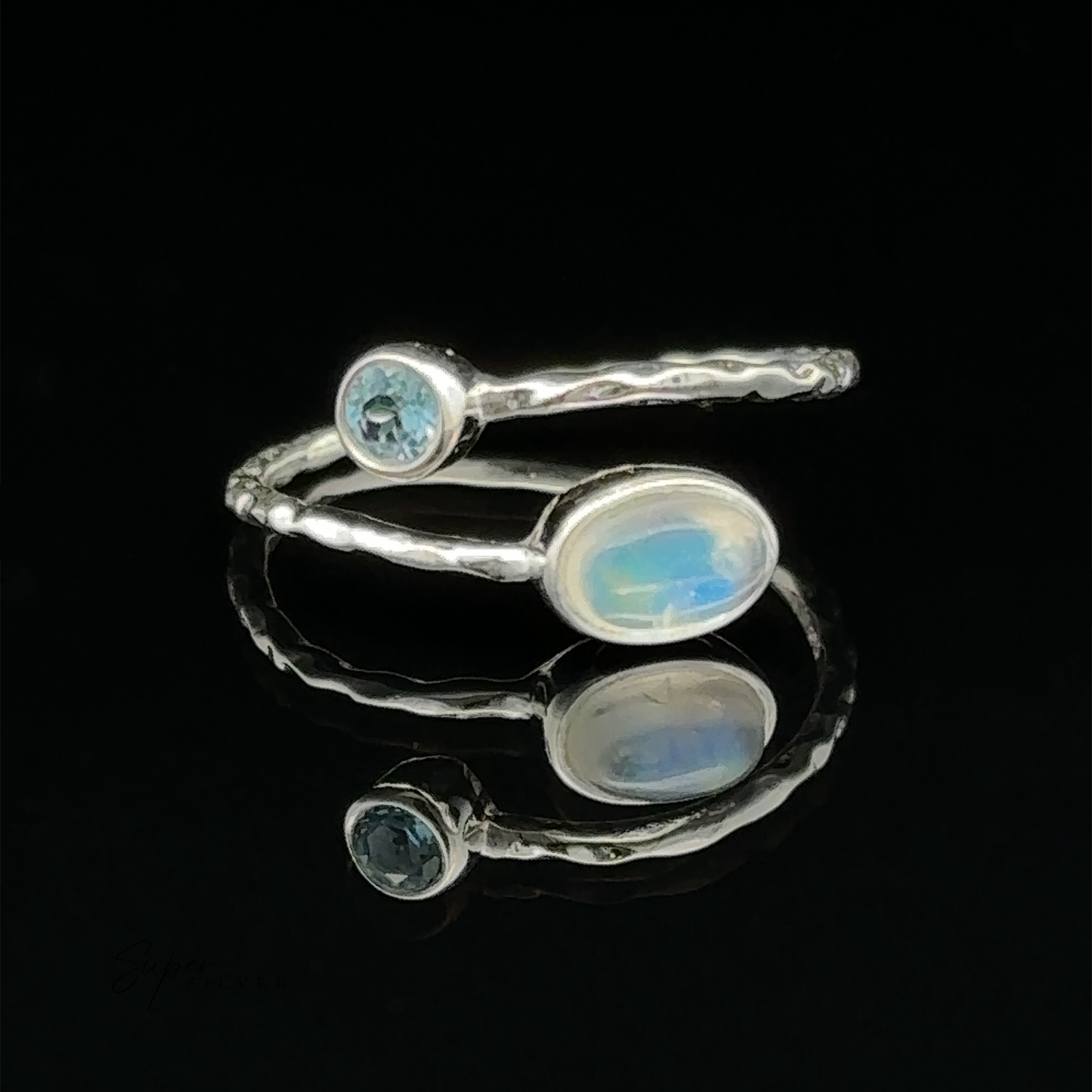 
                  
                    Textured Adjustable Band with Adorned Gemstones with a blue topaz and an opal gemstone on a reflective surface against a black background.
                  
                