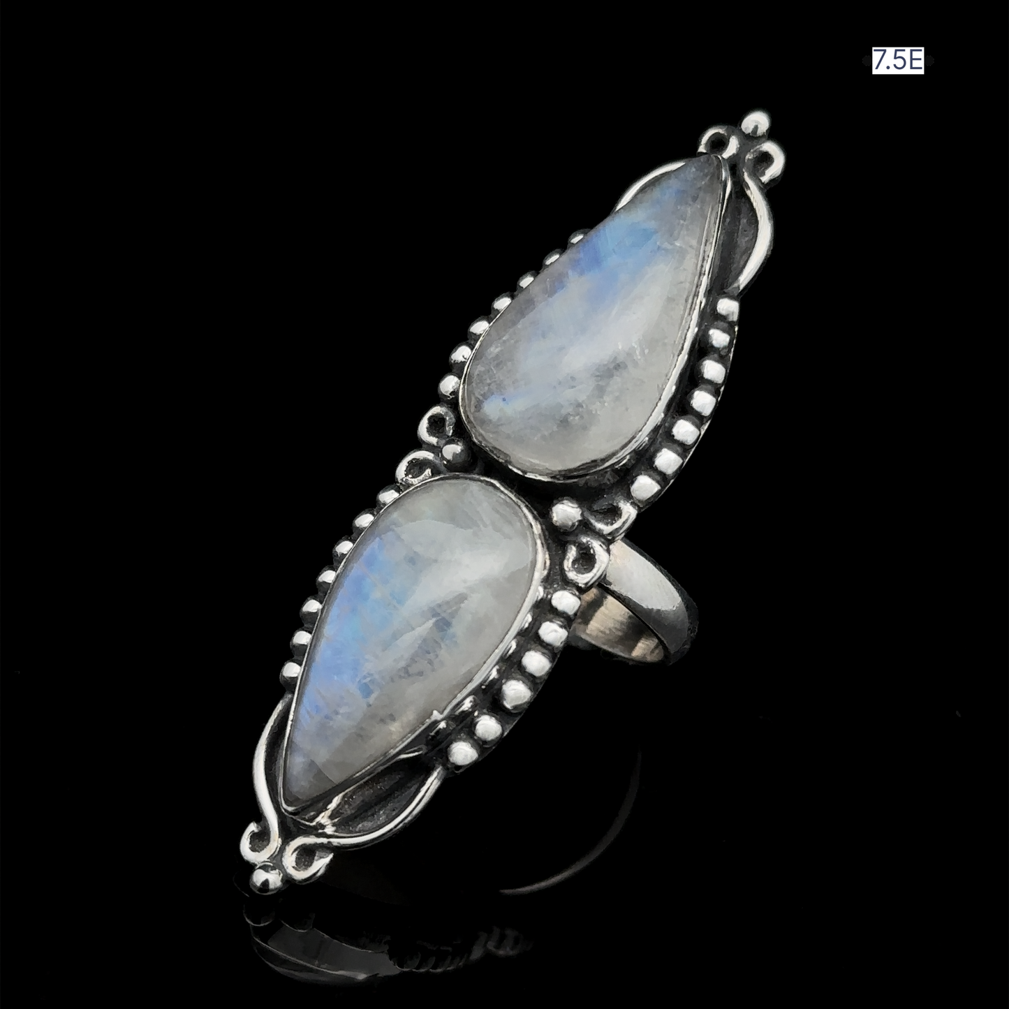 
                  
                    Introducing the Long Double Teardrop Moonstone Ring: A stunning statement piece adorned with two large, teardrop-shaped moonstone gems set vertically in sterling silver, featuring intricate beadwork on a black background. Available in size 7.5.
                  
                