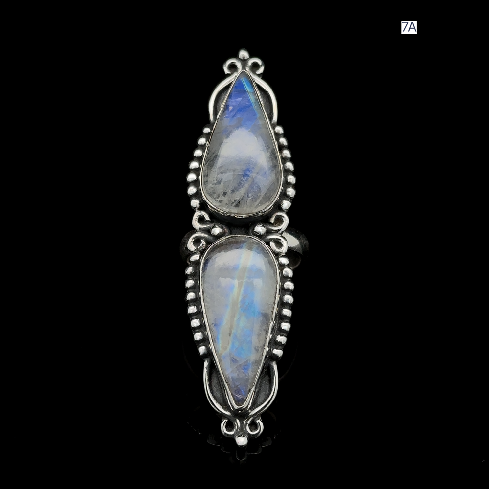 
                  
                    The Long Double Teardrop Moonstone Ring is a sterling silver piece that features two vertically set elongated teardrop-shaped moonstones, adorned with intricate beadwork on a black background, making it a captivating statement accessory.
                  
                