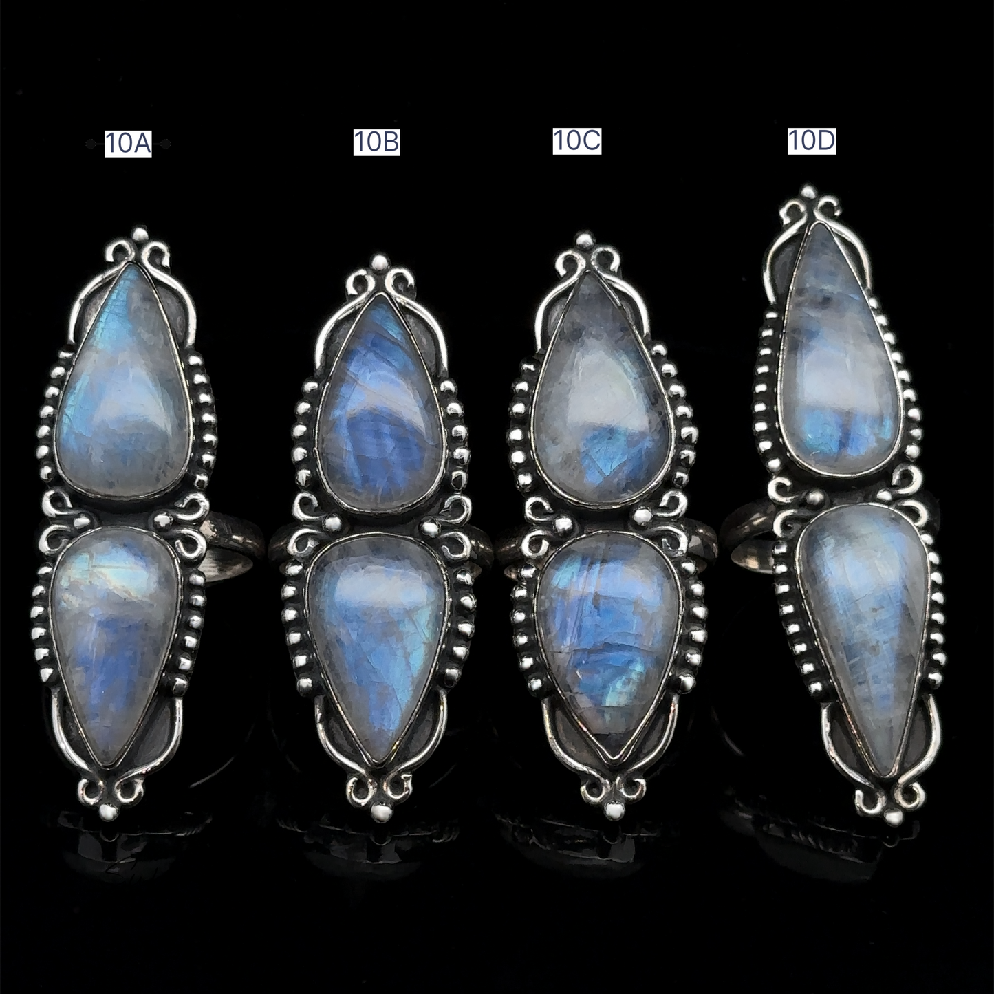 
                  
                    Four Long Double Teardrop Moonstone Rings, labeled 10A, 10B, 10C, and 10D, are arranged in a row against a black background. Each statement ring gleams elegantly, showcasing the exquisite craftsmanship and stunning allure of moonstone.
                  
                