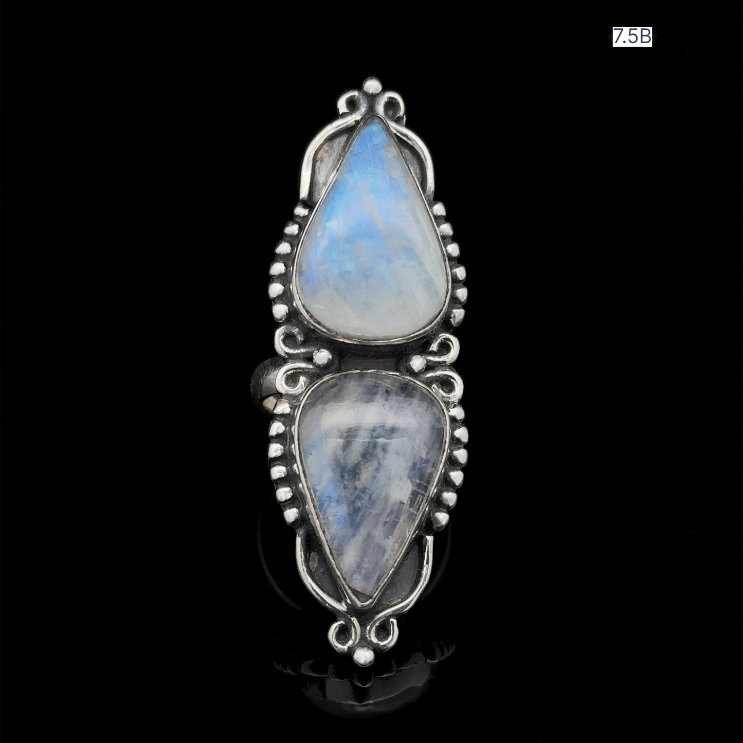 
                  
                    Long Double Teardrop Moonstone Ring featuring two vertically aligned teardrop-shaped moonstones on a black background. The intricate metalwork detailing is crafted from sterling silver, and the ring is labeled "7.5B" in the top right corner.
                  
                