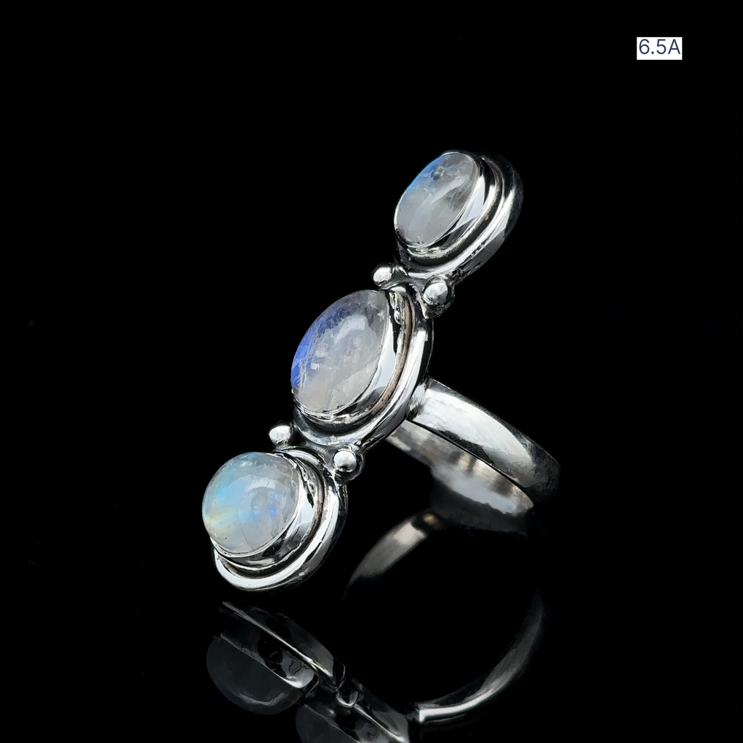 
                  
                    Triple Moonstone Ring crafted in sterling silver, featuring three round moonstones set against a black backdrop that exudes goddess energy. Marked with "6.5A" in the upper right corner.
                  
                