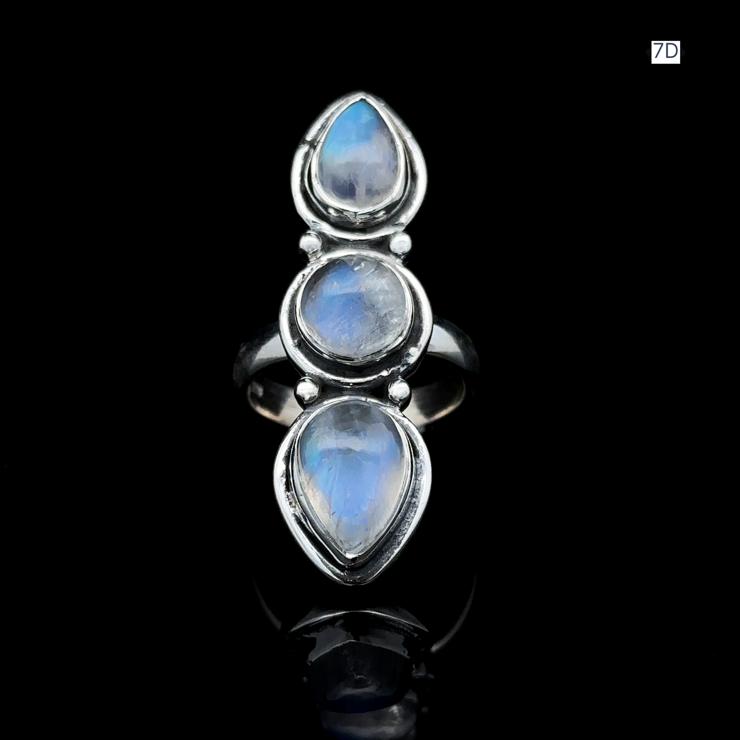 
                  
                    Triple Moonstone Ring crafted in sterling silver, featuring three vertically-set teardrop-shaped moonstones that capture goddess energy against a bold black backdrop.
                  
                