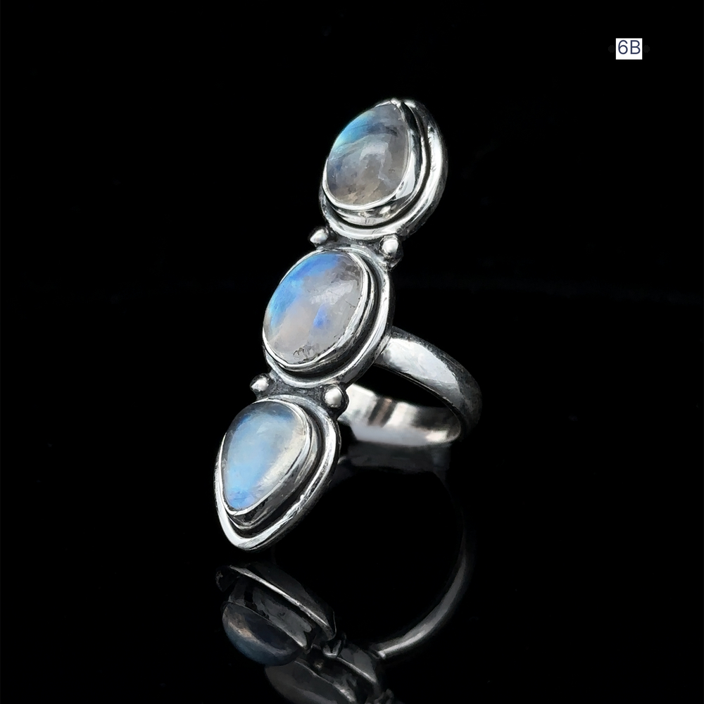 
                  
                    Triple Moonstone Ring crafted from sterling silver, showcasing three oval moonstones on a reflective black surface, channeling goddess energy.
                  
                