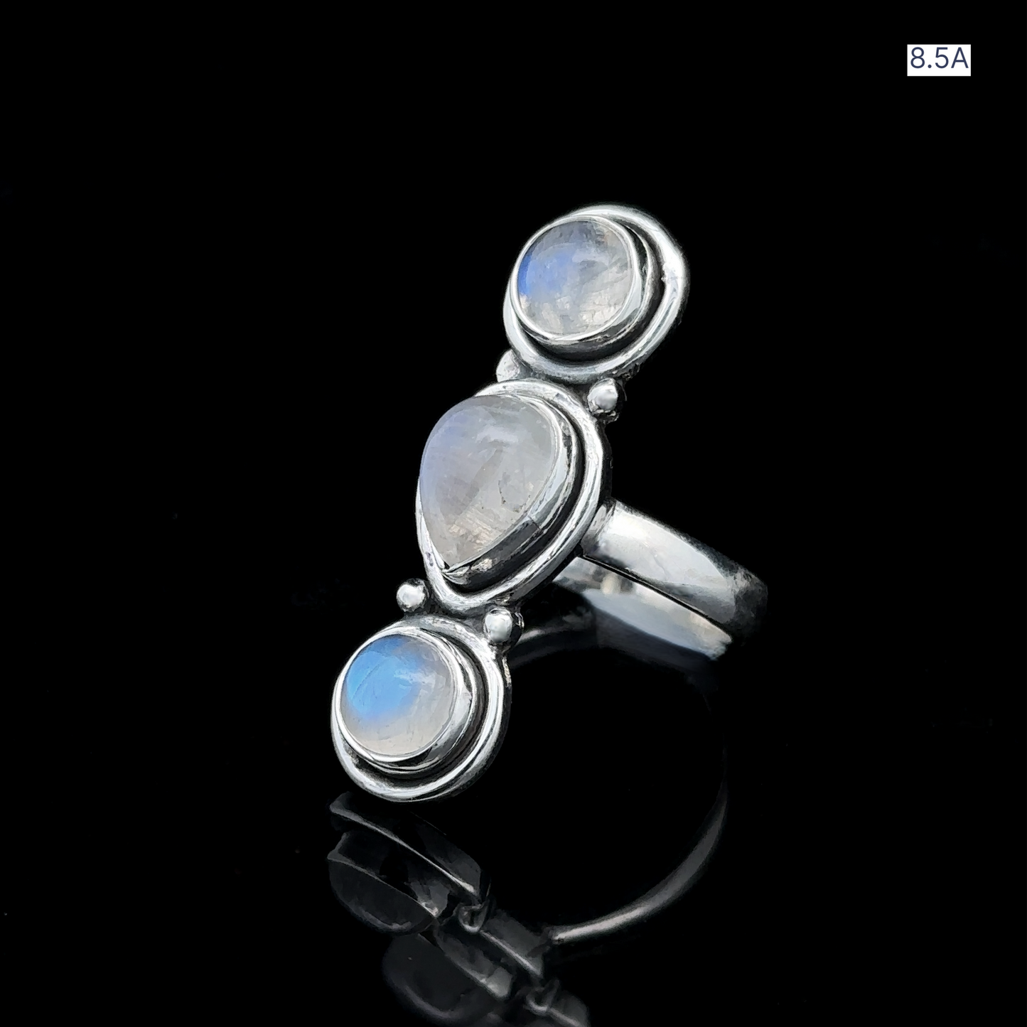 
                  
                    Triple Moonstone Ring crafted from sterling silver features a teardrop-shaped moonstone centerpiece flanked by two round moonstones. The design channels goddess energy and is presented against a black background, marked with the label "8.5A" in the corner.
                  
                