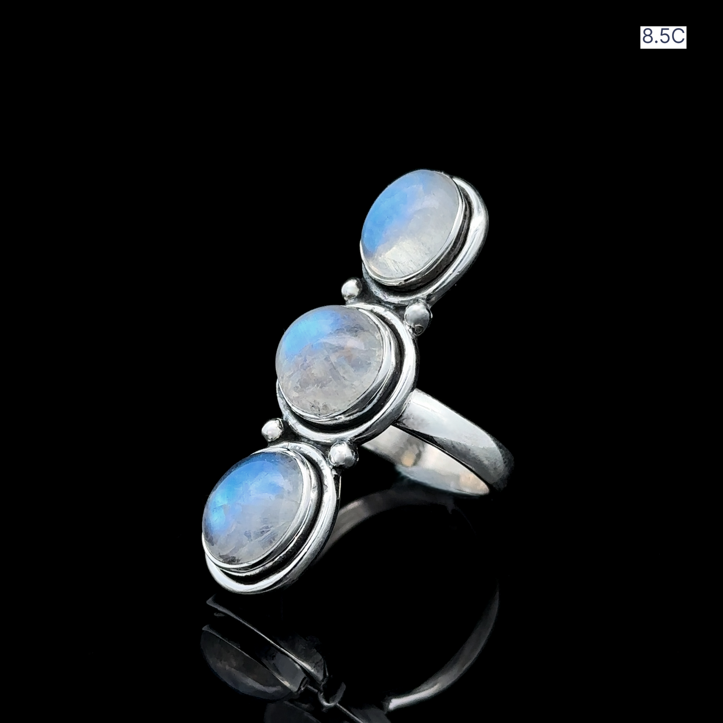 
                  
                    Triple Moonstone Ring showcasing three radiant moonstone gems arranged vertically in sterling silver, exuding goddess energy against a black background.
                  
                