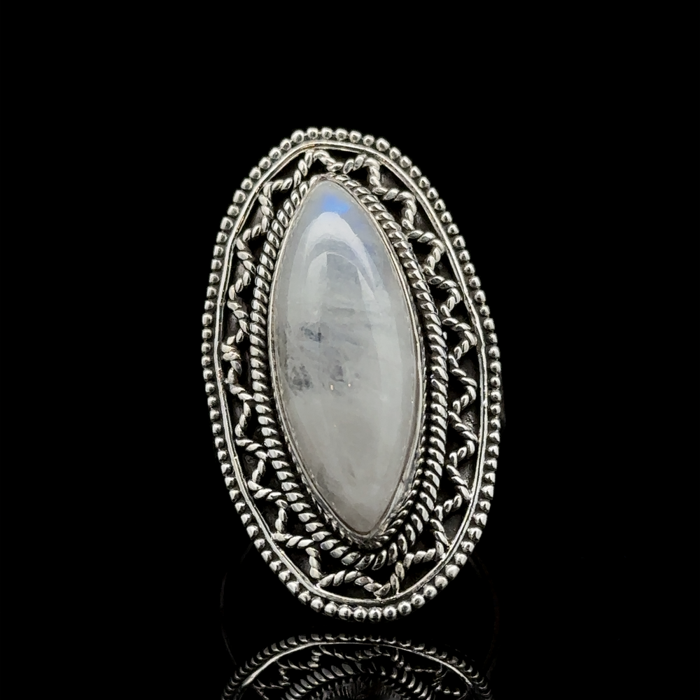 
                  
                    A Marquise Shaped Gemstone Ring With Vintage Shield Border with an elongated oval moonstone set in an intricately detailed filigree band against a black background, this piece offers a Bohemian twist to your style.
                  
                