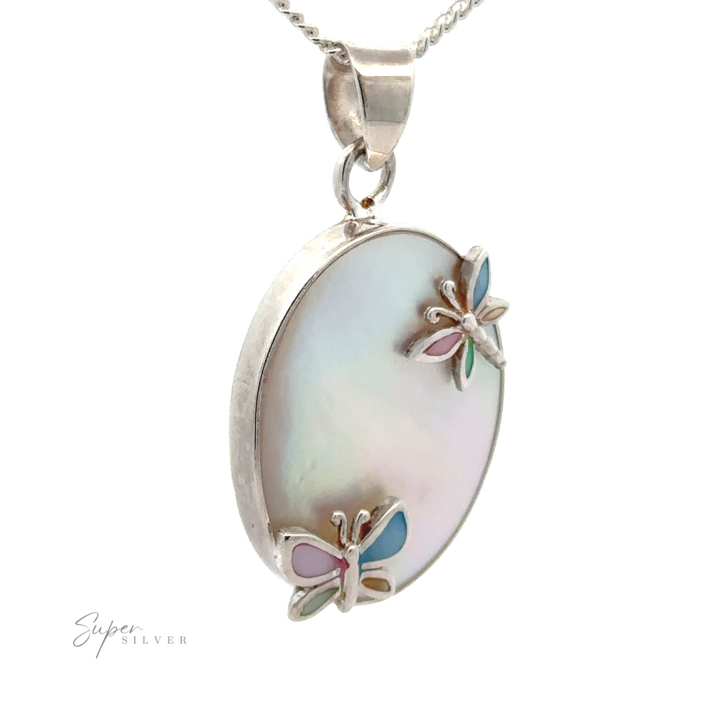 A Mother of Pearl Pendant with Butterflies and Dragonflies featuring a polished oval stone, accented with two delicate butterfly decorations in pastel colors. The pendant, enhanced by a mother-of-pearl sheen, hangs elegantly from a silver chain.