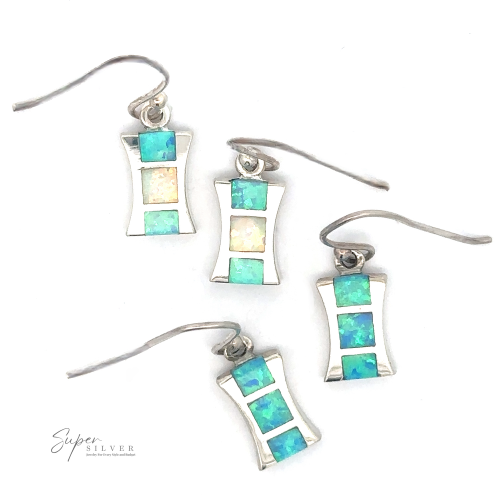 
                  
                    Four pairs of Freeform Lab-Created Opal Earrings featuring rectangular designs adorned with small square blue and white created opal gemstones. The image shows the earrings arranged on a white background.
                  
                