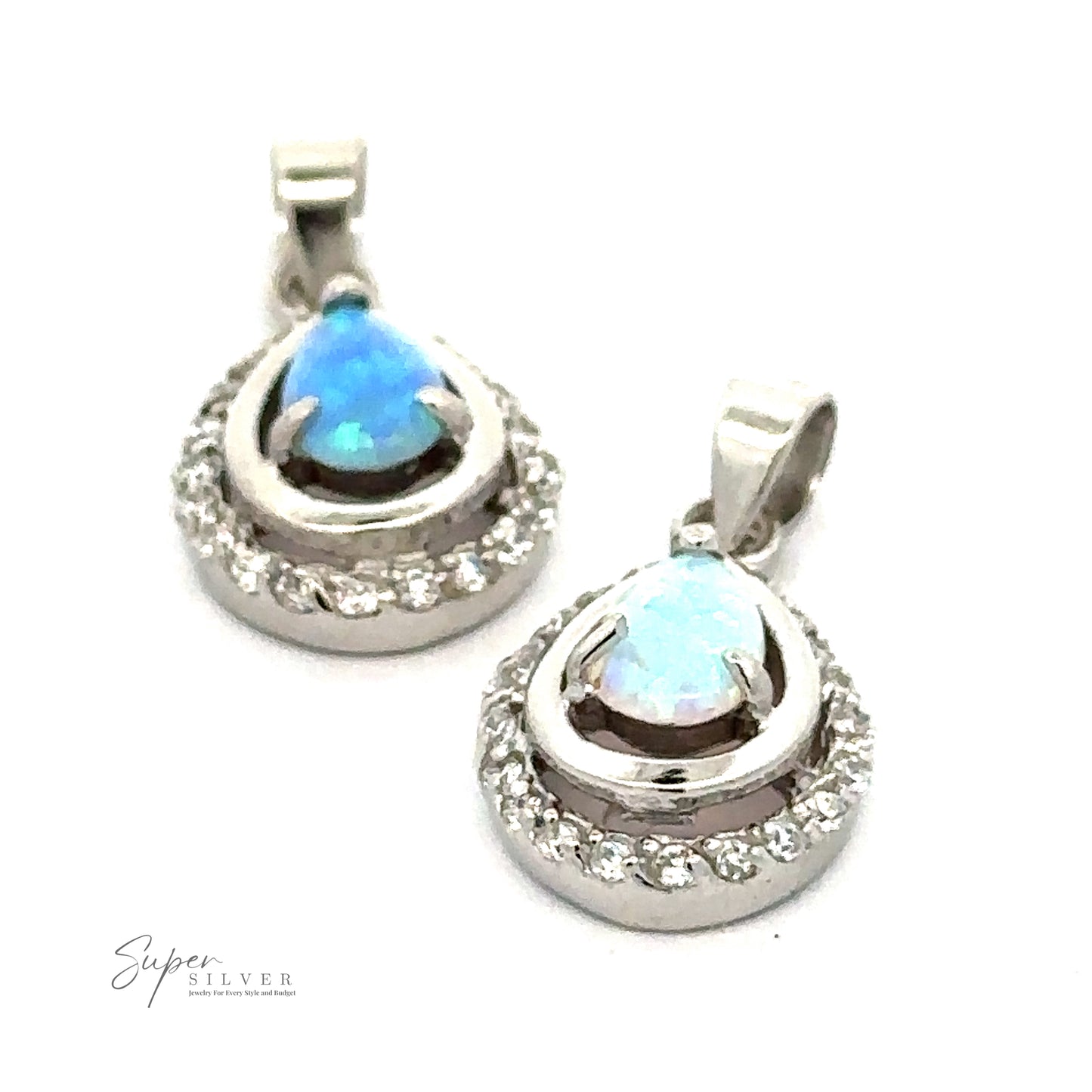 
                  
                    Two teardrop-shaped Opal Pendants with Cubic Zirconia feature blue opal stones set in silver, surrounded by small, clear crystals and cubic zirconia stones. The Super Silver logo is visible at the bottom left.
                  
                