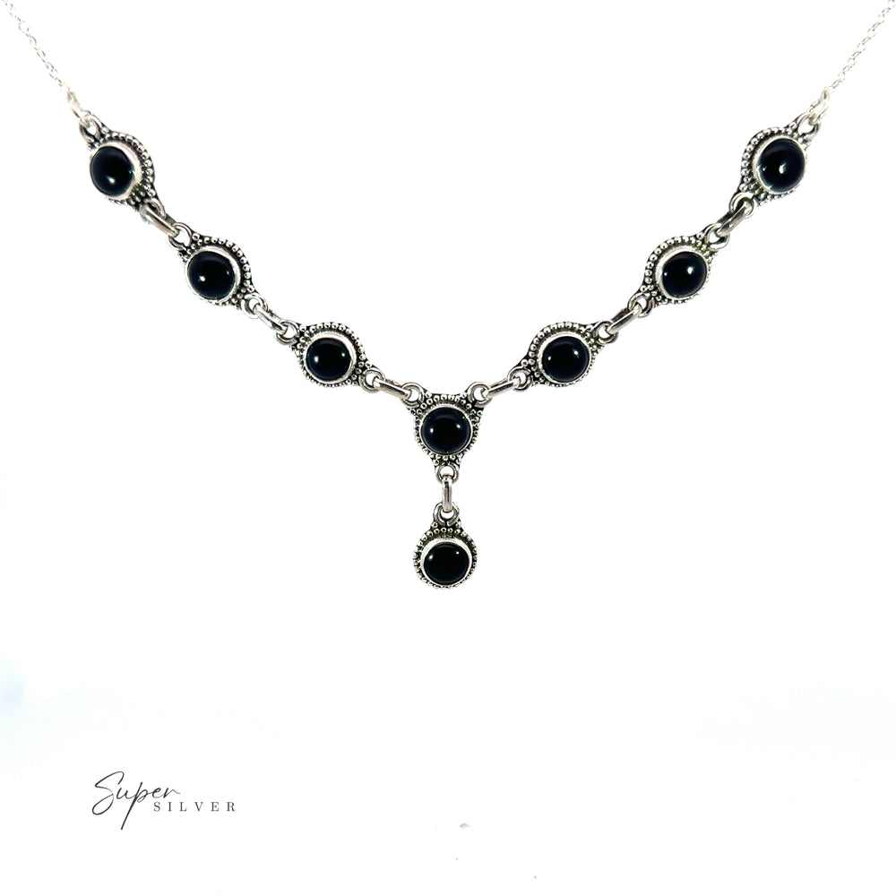 
                  
                    This Round Gemstone Y Necklace with Ball Border features interconnected circular black stones on a white background, epitomizing bohemian style jewelry. The Round Gemstone Y Necklace with Ball Border design is completed with a dangling pendant that showcases an additional black stone at the bottom center.
                  
                