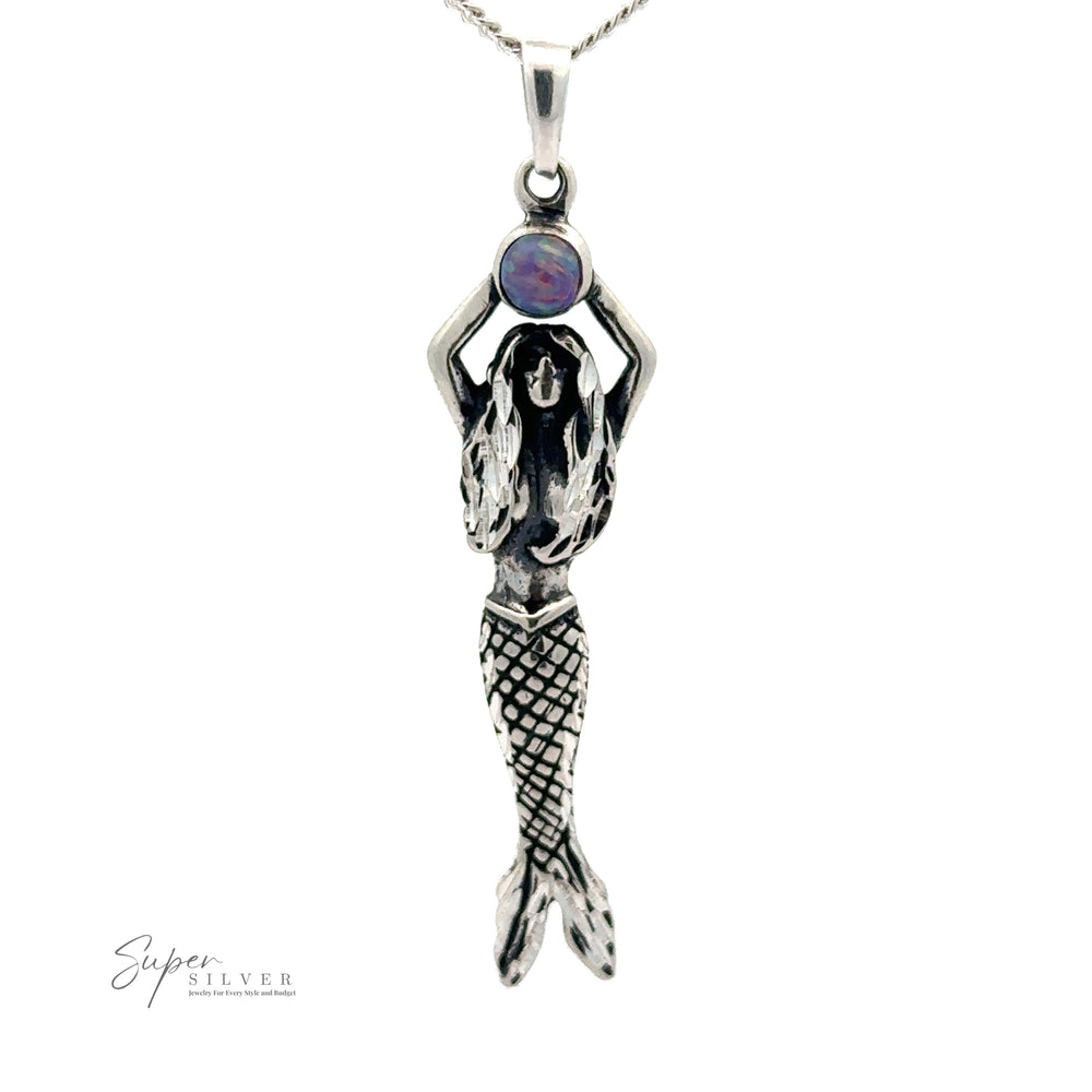 
                  
                    Mermaid And Opal Pendant with her hands raised, holding an opal stone. The mermaid has detailed scales on her tail and long flowing hair, crafted from oxidized silver. The logo "Super Silver" is visible at the bottom left.
                  
                