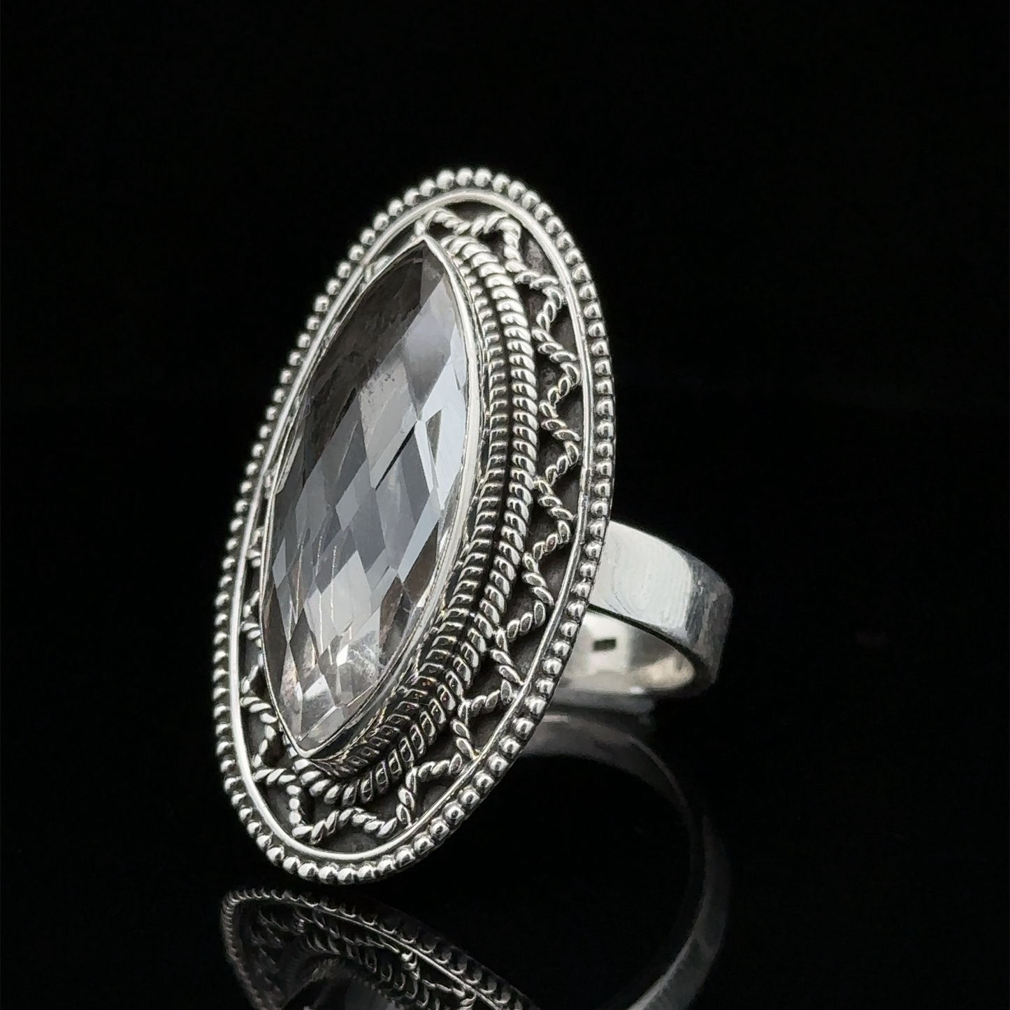 
                  
                    A Bohemian twist on elegance, this Marquise Shaped Gemstone Ring With Vintage Shield Border features an oval-shaped, faceted clear gemstone set in an ornate bezel against a black background.
                  
                