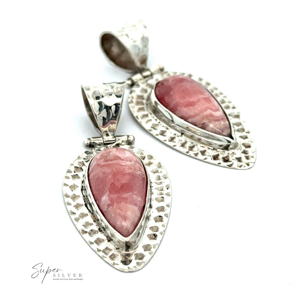 
                  
                    Two Rhodochrosite Hammered Teardrop Pendants featuring pink teardrop-shaped rhodochrosite stones set within textured silver frames display beneath a logo reading "Super Silver." Each piece boasts a unique design and is believed to possess emotional healing properties.
                  
                