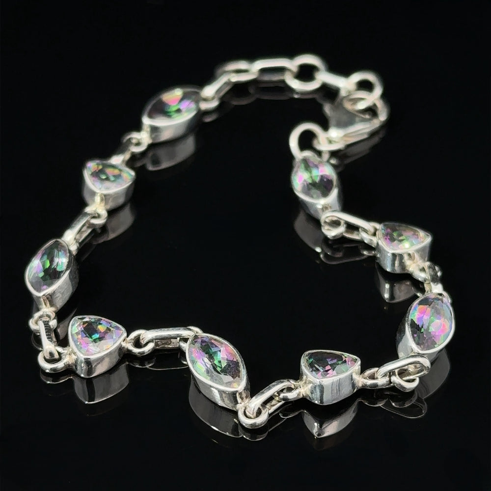 
                  
                    A sterling silver bracelet featuring marquise-shaped crystals with multicolored reflections, displayed on a black background, exudes the mystic allure of the Rainbow Mystic Topaz Marquise and Triangle Shape Link Bracelet.
                  
                