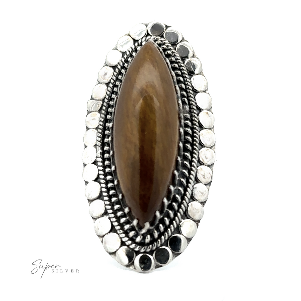 
                  
                    A close-up of a Statement Marquise Shaped Gemstone Ring featuring a brown marquise-shaped gemstone, encased in an ornate silver setting that boasts intricate details and circular patterns, epitomizing bohemian jewelry.
                  
                
