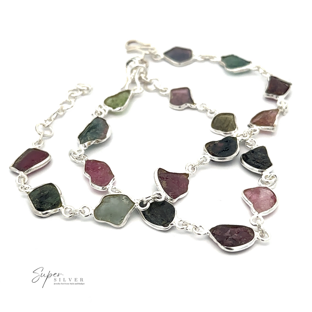 A Rough Tourmaline Bracelet featuring irregularly shaped, multicolored rough tourmaline stones, arranged in a linked chain design. The product exudes earthy elegance and is branded with 