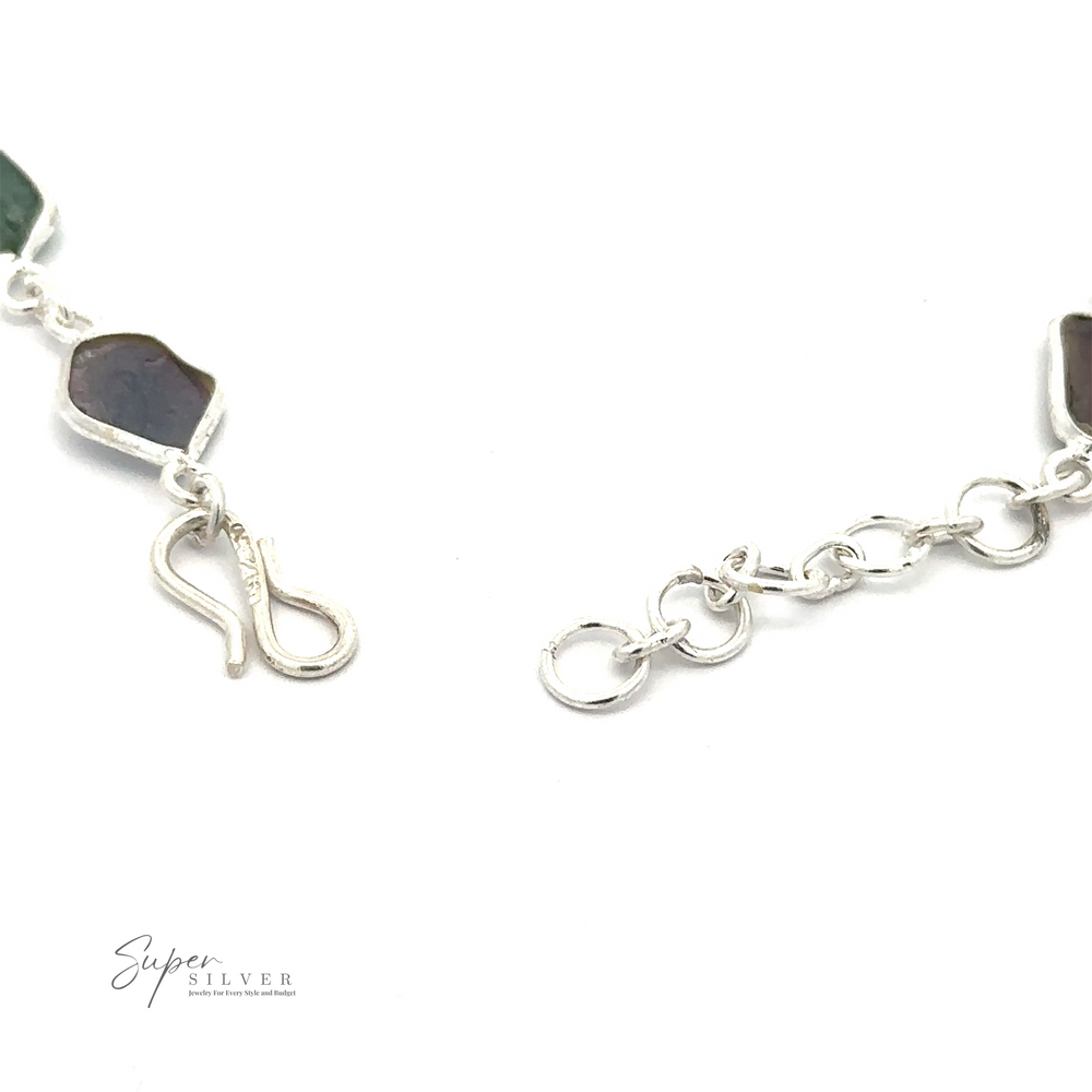
                  
                    Close-up of a Rough Tourmaline Bracelet with a hook clasp and rough tourmaline stones in green and dark hues, exuding earthy elegance. The logo "Super Silver" is visible in the bottom left corner.
                  
                