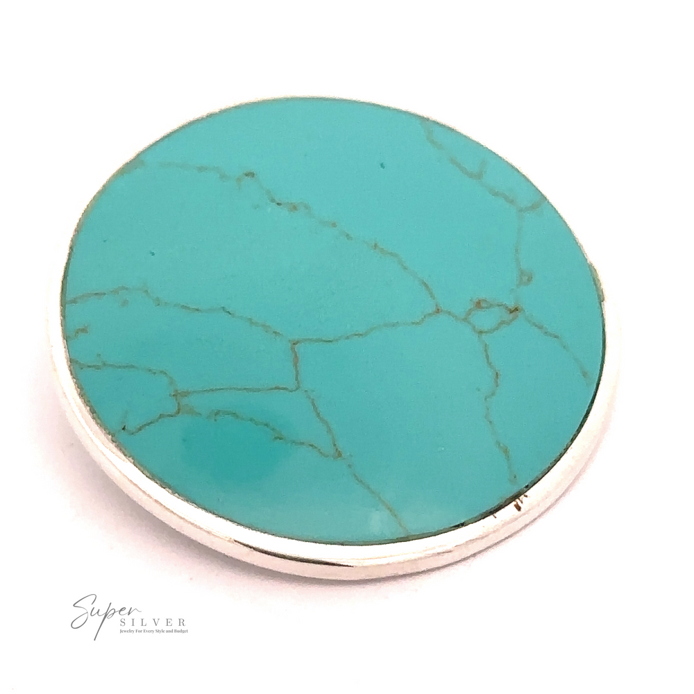 A Large Round Turquoise Pendant set in a thin, silver-colored metal frame. The stone has natural veining and a polished surface, perfectly embodying minimalist jewelry aesthetics.