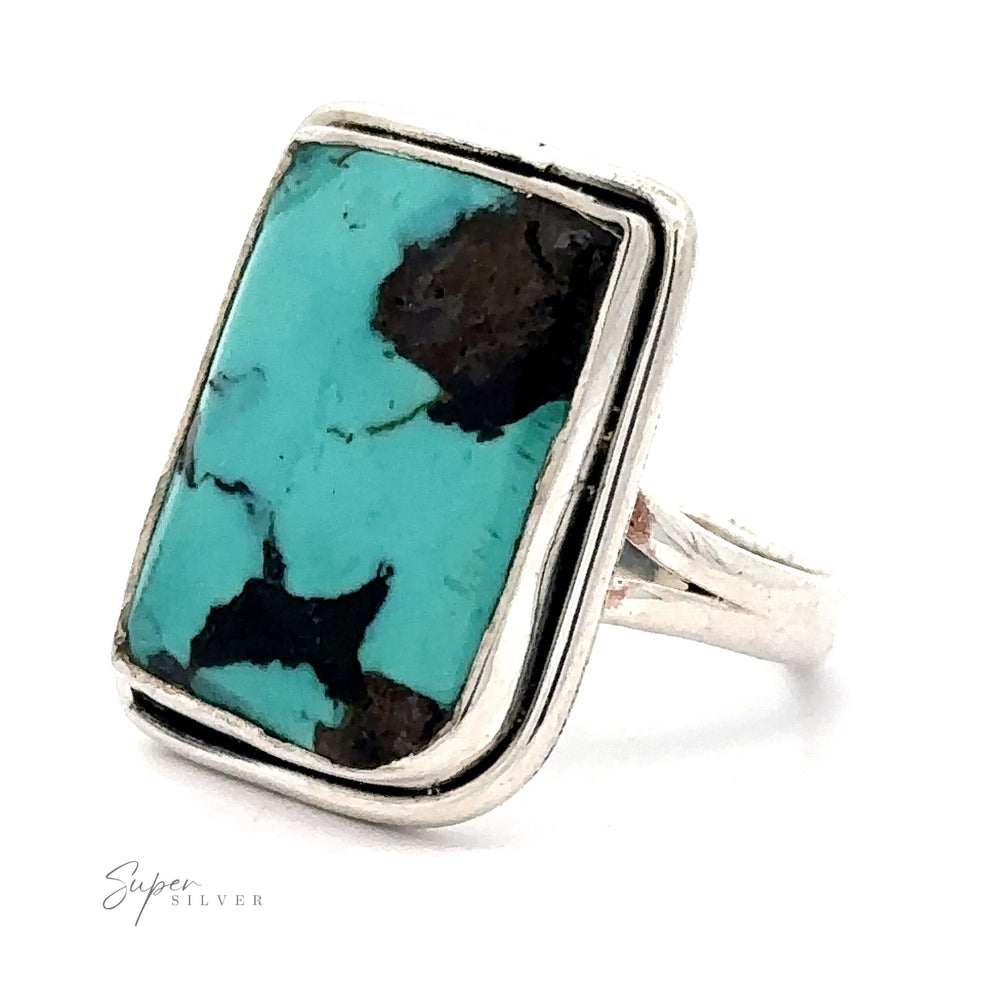 A Rectangular Natural Turquoise Ring With Plain Border featuring a large rectangular turquoise stone with black inclusions. The stone is set in a simple bezel setting, making it a stunning piece of natural turquoise jewelry.