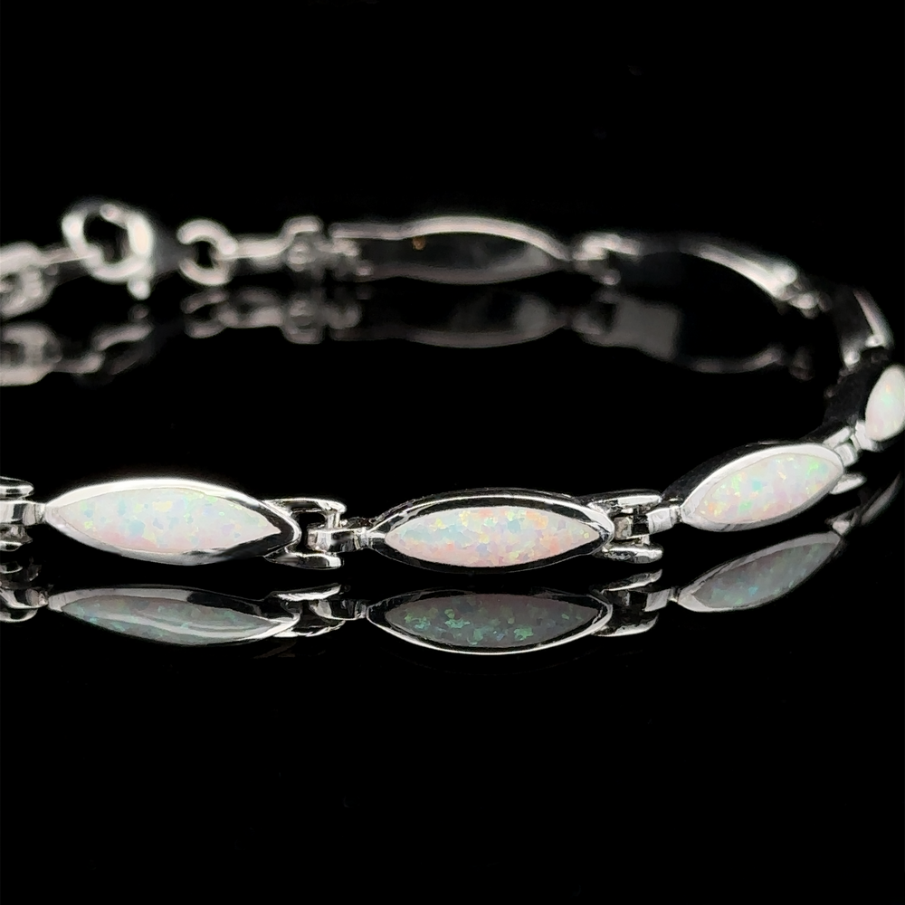 
                  
                    The Marquise Shaped Lab-Created Opal Bracelet, showcasing a contemporary aesthetic with silver and marquise-shaped lab-created opal gemstones, is elegantly displayed against a black background, reflecting light beautifully.
                  
                