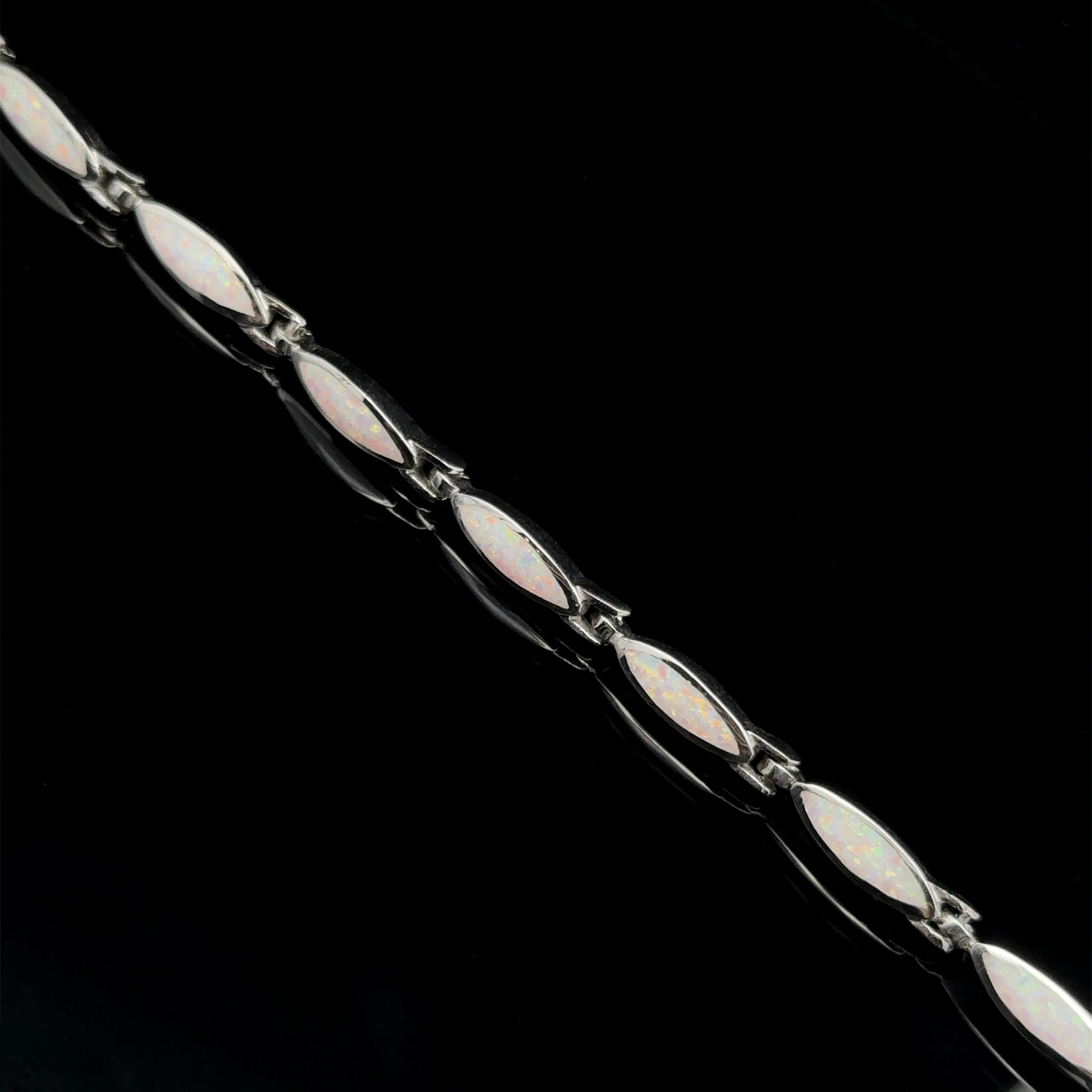 
                  
                    A stunning Marquise Shaped Lab-Created Opal Bracelet in .925 Sterling Silver, featuring marquise-shaped opal stones set in a linked chain, displayed diagonally on a black background.
                  
                