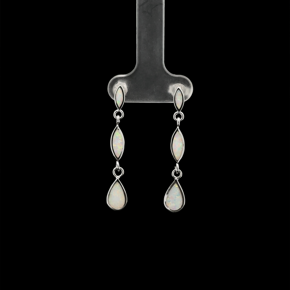 
                  
                    The Elegant Lab-Created Opal Earrings, featuring three linked, lab-created opal stones in an elegant oval shape, are displayed against a black background on a metal stand.
                  
                