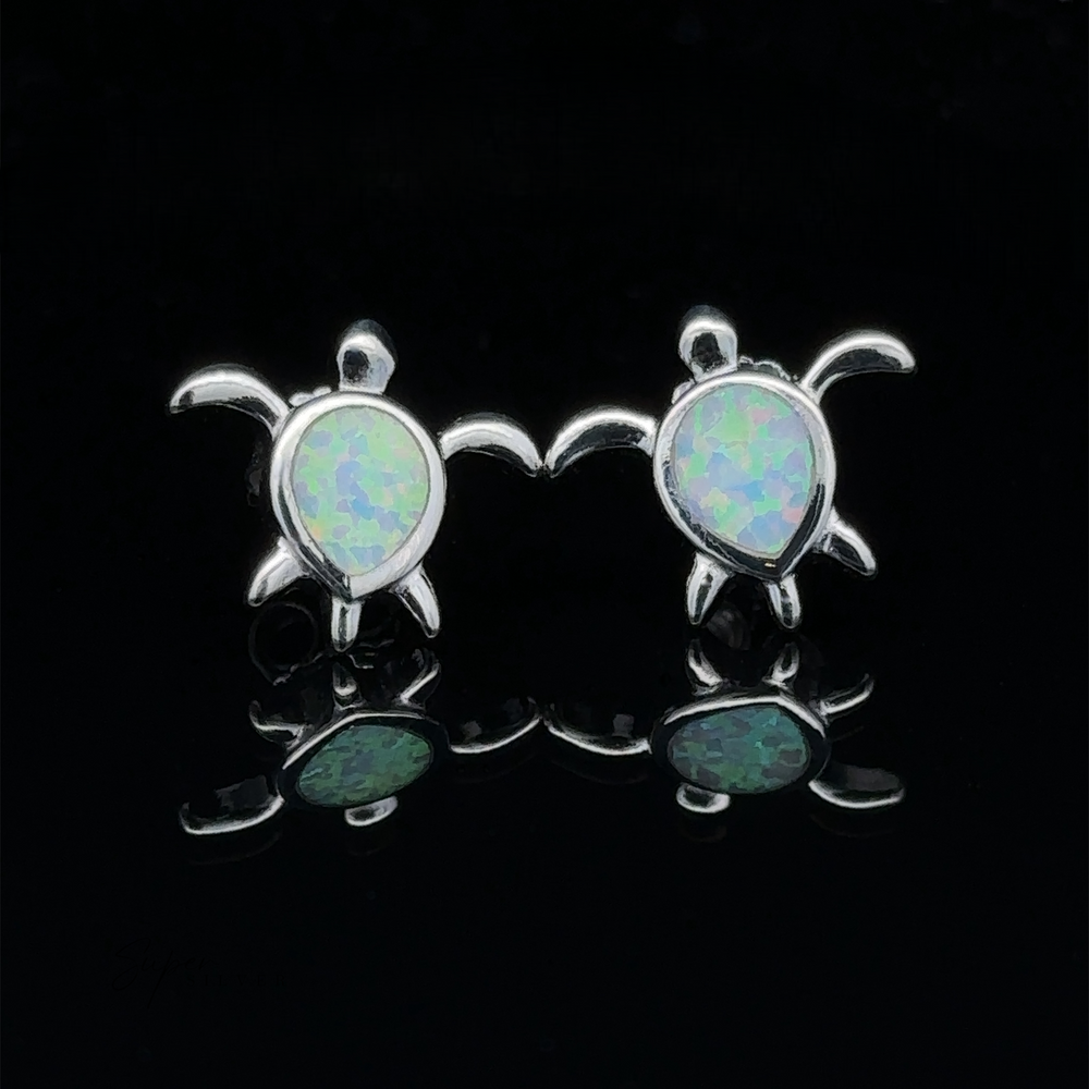 
                  
                    Introducing the Simple Lab-Created Opal Turtle Studs, a pair of sterling silver earrings featuring sea turtle designs with lab-created opal inlays set against a black background.
                  
                